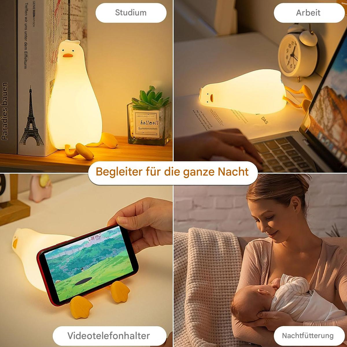 Vier Bilder mit einer weißen, entenförmigen Lampe und Text. Die Lampe steht auf einem Schreibtisch und wird von einem Baby benutzt.