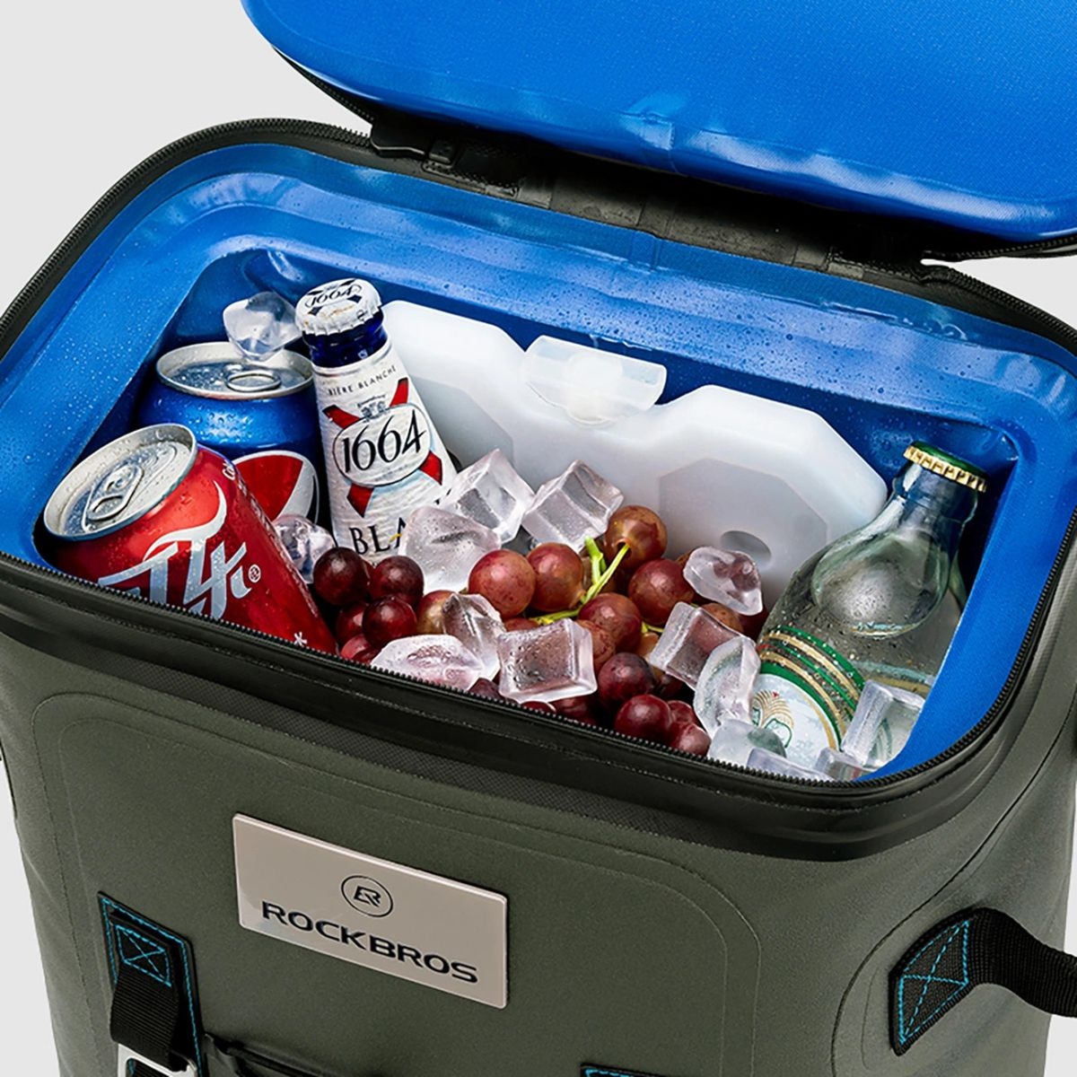 Offene Kühltasche mit Getränken, Eis und Trauben darin, auf weißem Hintergrund.