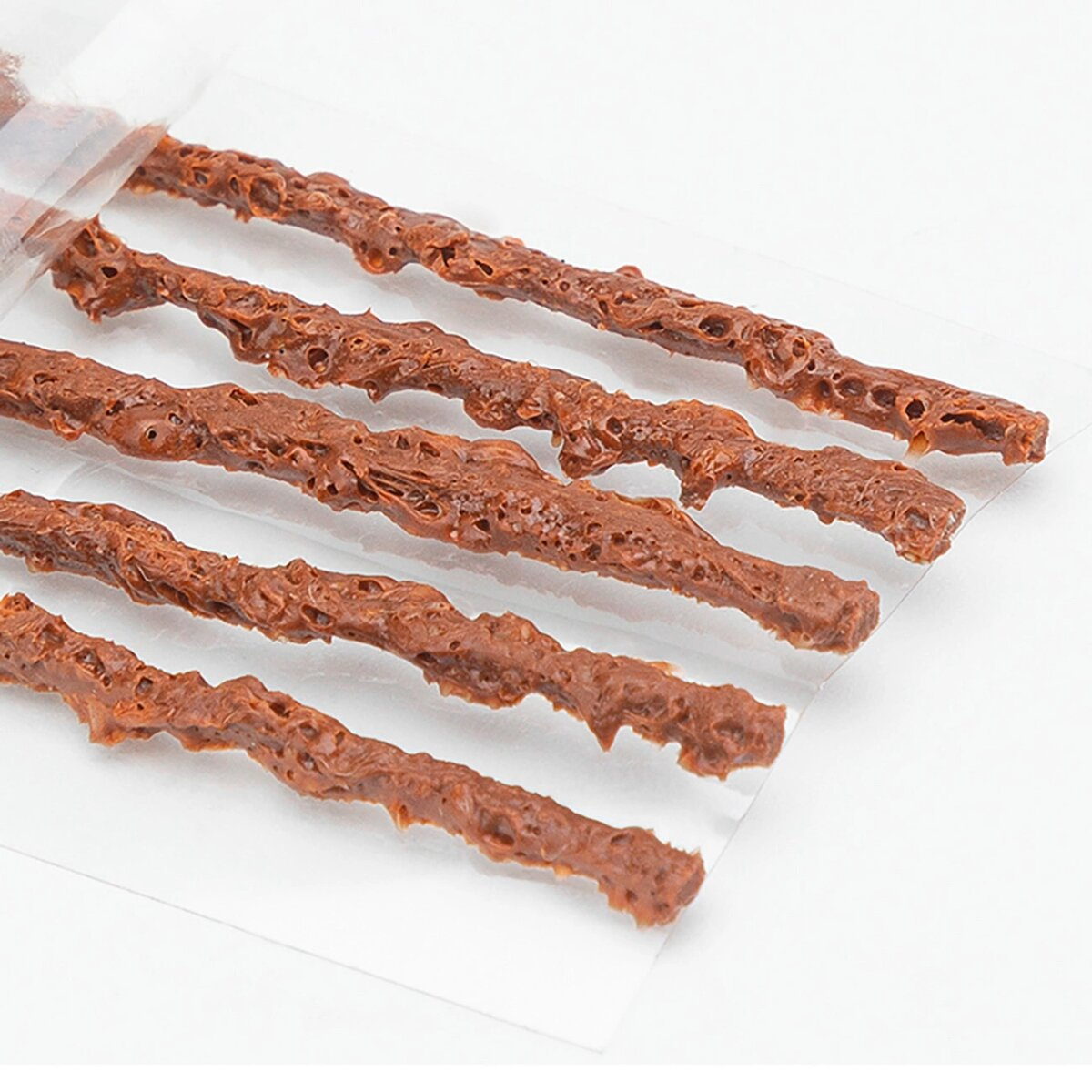 Nahaufnahme mehrerer schokoladenüberzogener Brezelstangen in einer durchsichtigen Plastikverpackung.