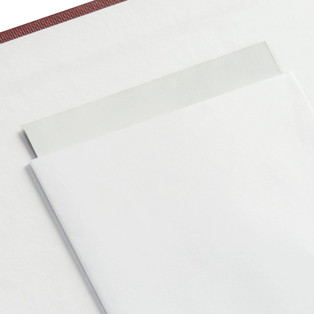 Otwarty album fotograficzny z białymi stronami i folią ochronną na teksturowanej powierzchni.