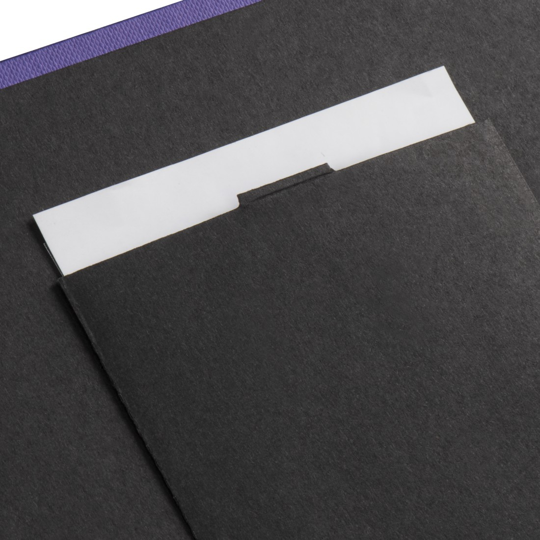 Otwarty album ze zdjęciami. Czarne strony. Biała kieszeń. Fioletowa ramka.