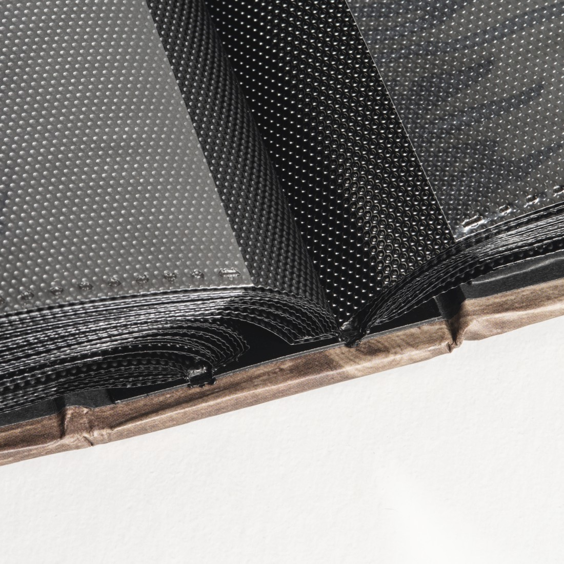 Otwarty album ze zdjęciami. Czarny album. Teksturowane czarne strony. Brązowa okładka.