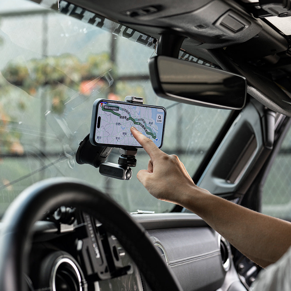 Ein im Auto montiertes Telefon zeigt eine Karte, mit einem Finger, der auf den Bildschirm zeigt.