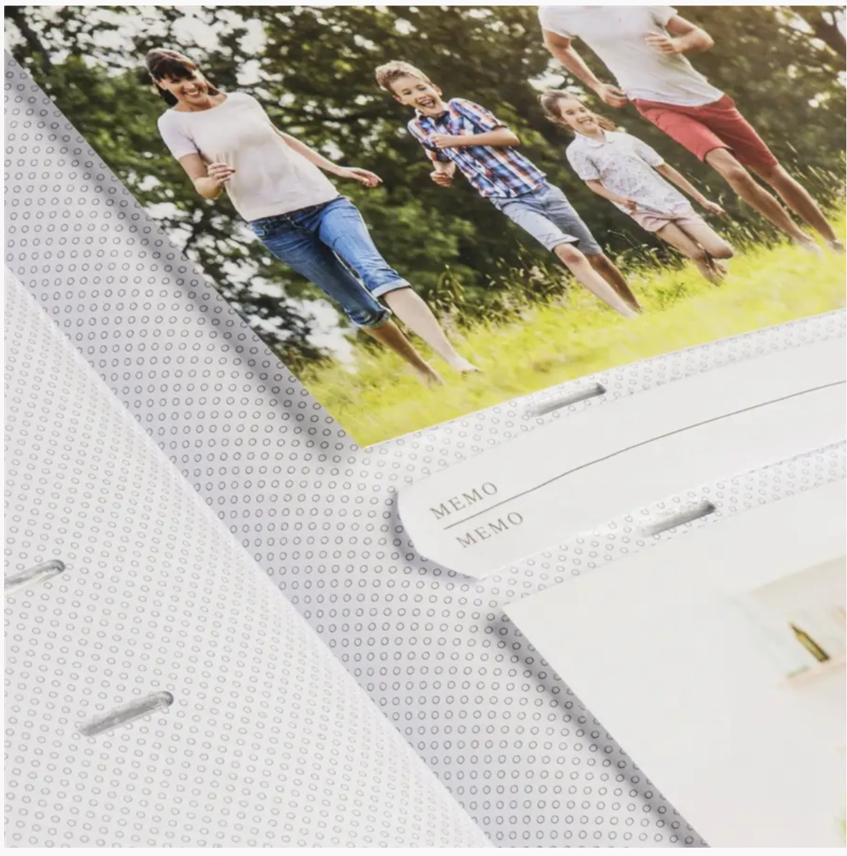 Otwarty album fotograficzny ze zdjęciami ludzi biegających po trawie. Widoczne są etykiety memo.