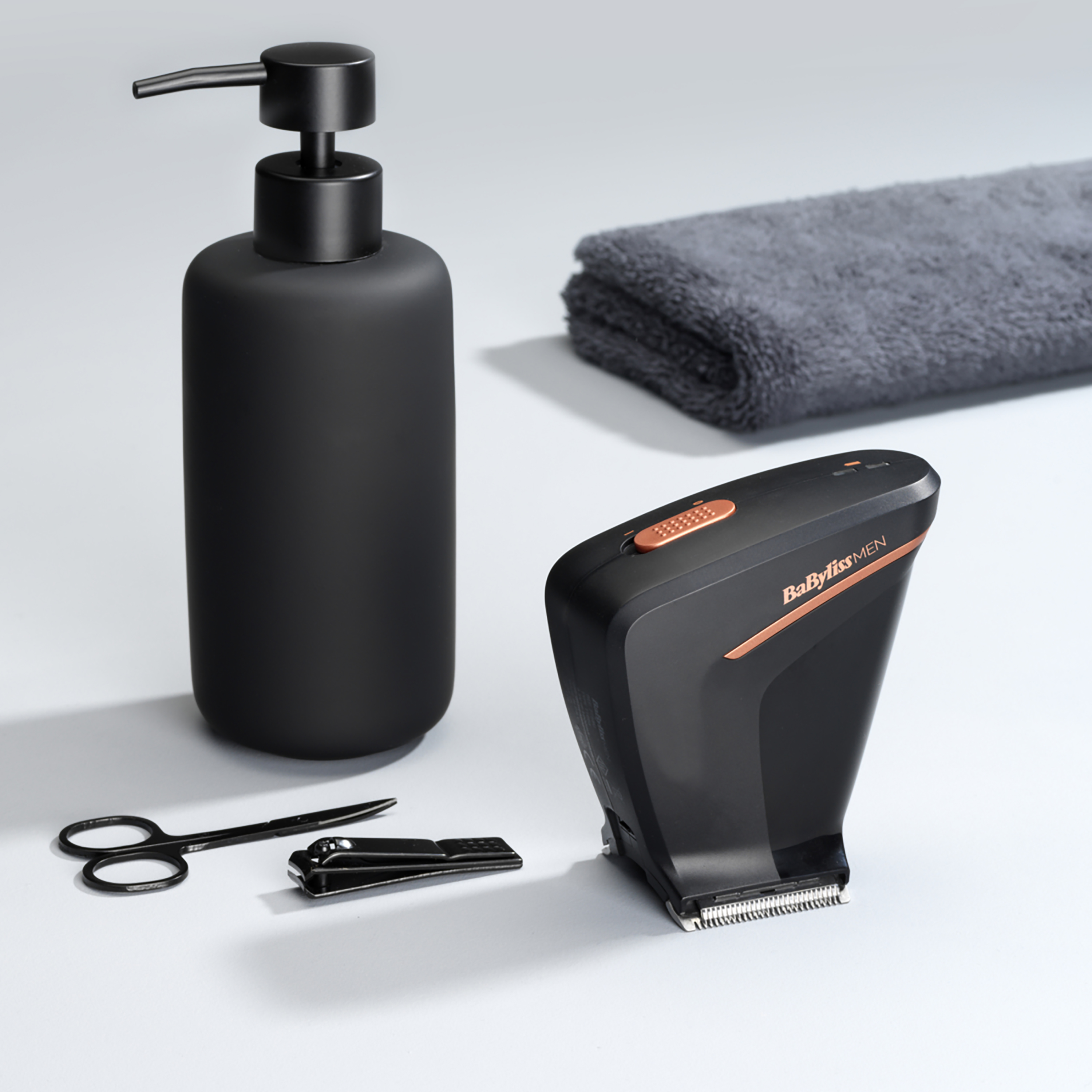 Schwarze Pumpflasche, Schere, Nagelknipser und ein schwarz-kupferfarbener Trimmer.