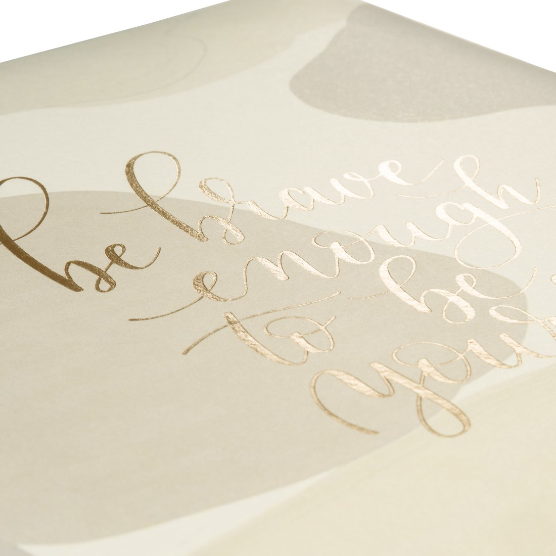 Primo piano di una copertina di libro con scritta dorata: 'be brave enough to be you' su sfondo beige.