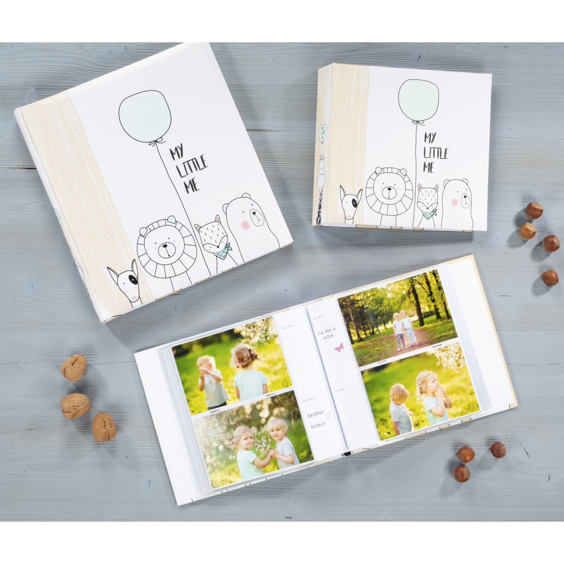 Otwarte albumy ze zdjęciami na drewnianym stole. Zdjęcia dziecka i rodziny. Orzechy.