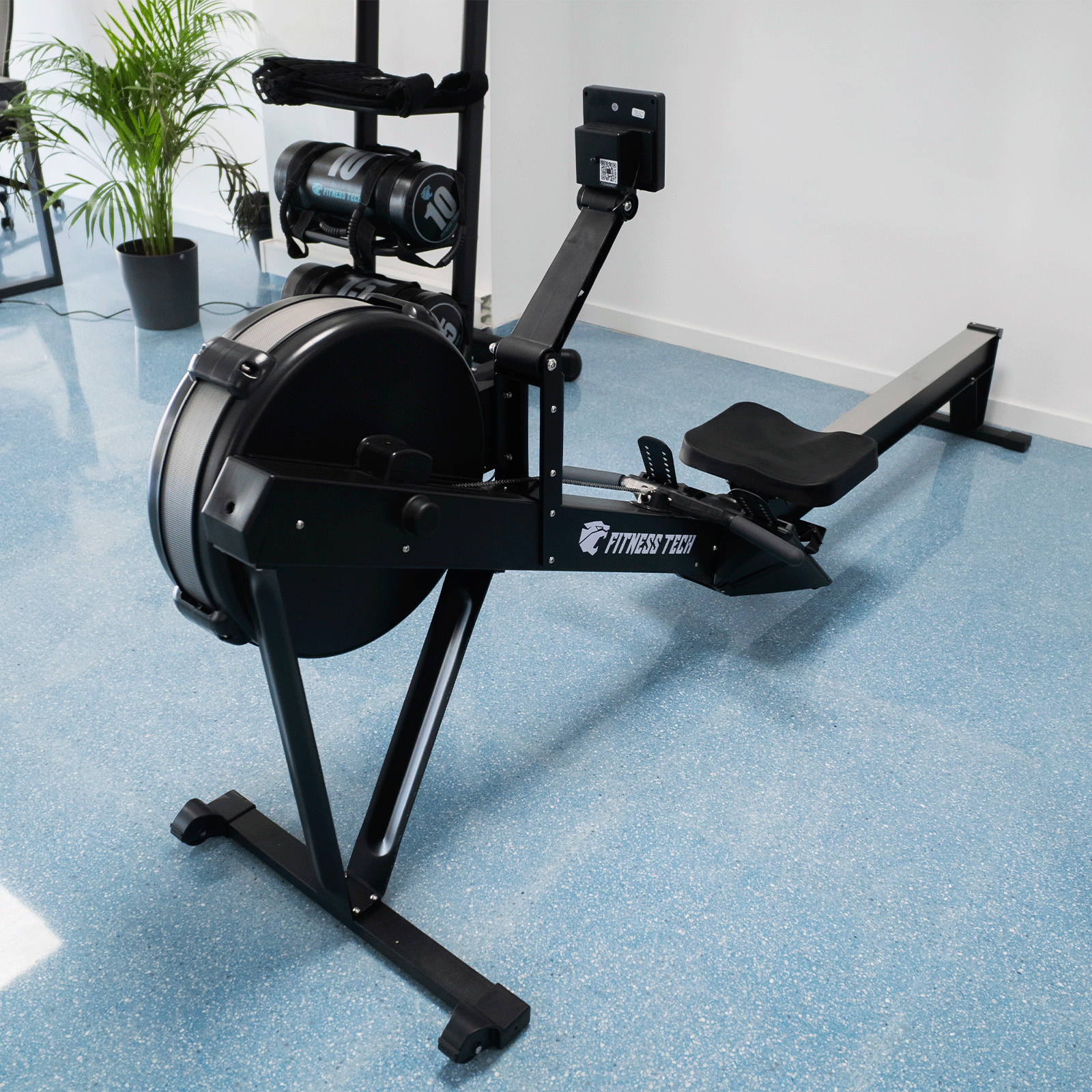 Rematore nero con logo 'FITNESS TECH', in una palestra con pavimento blu.