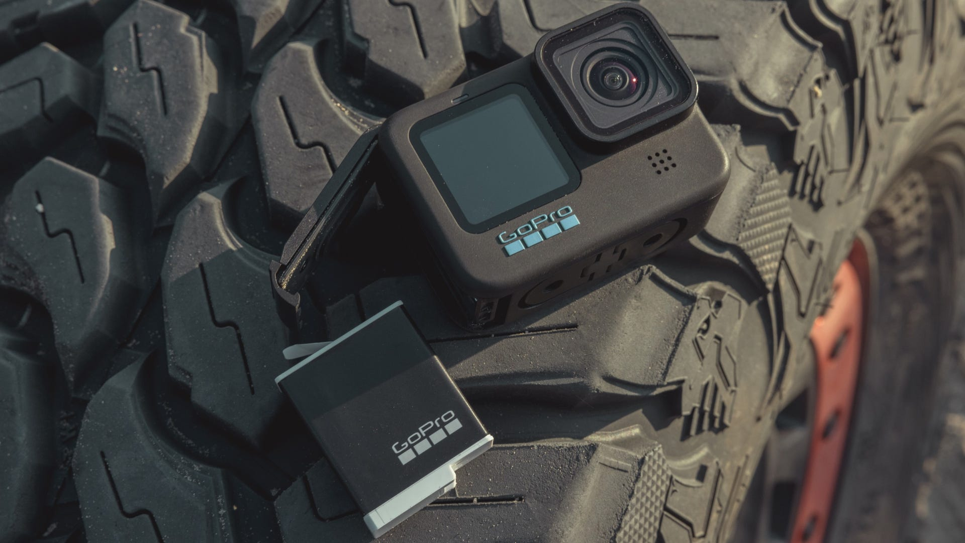 Kamera GoPro i bateria na oponie. Kamera jest czarna i ma logo GoPro.