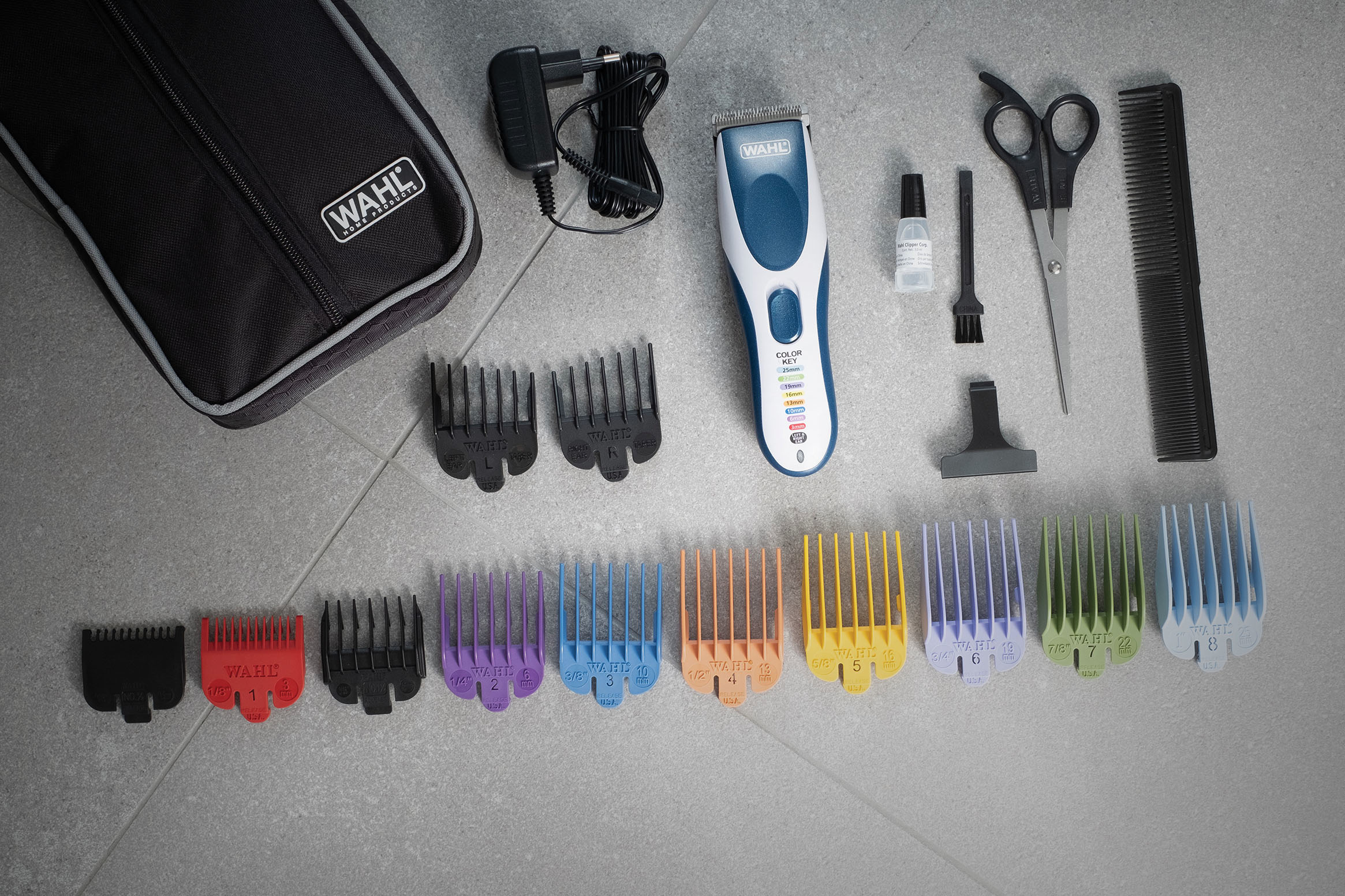 Kit de cortapelos con cortapelos, peines, tijeras y accesorios sobre superficie gris.