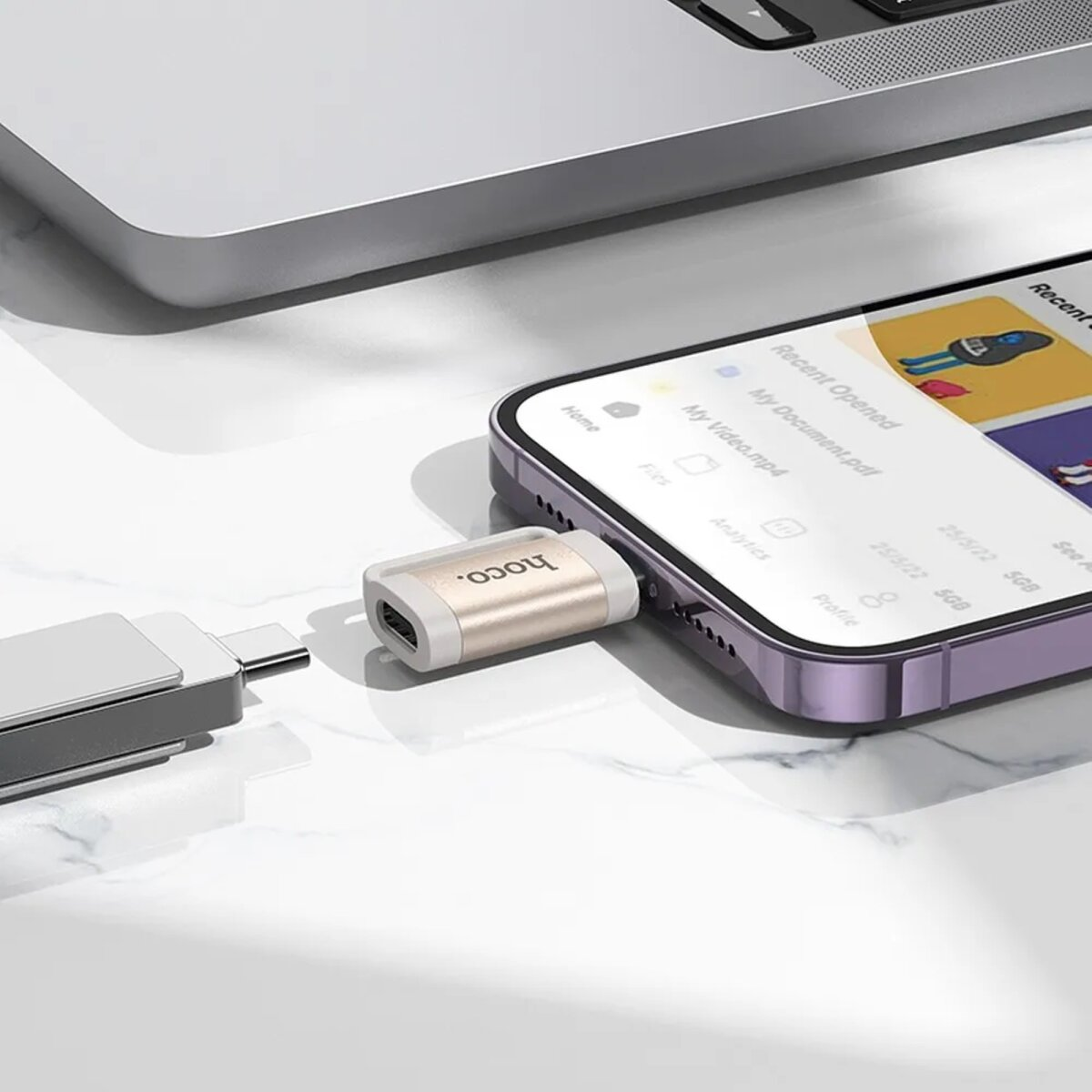 Adapter am Telefon, neben Laptop, auf Marmoroberfläche.