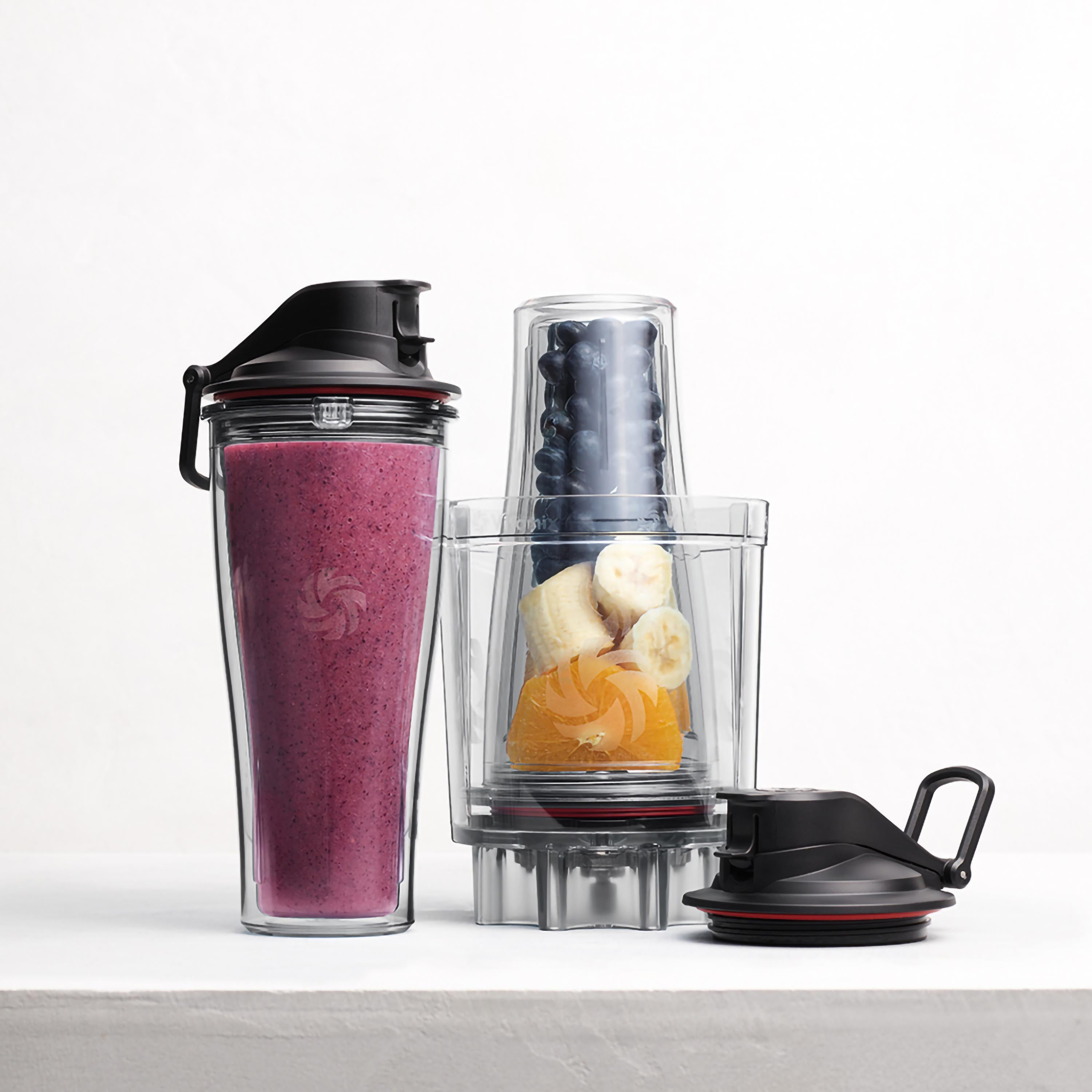 Mixer mit Zutaten: Smoothie, Blaubeeren, Bananenscheiben und Orangenscheiben.