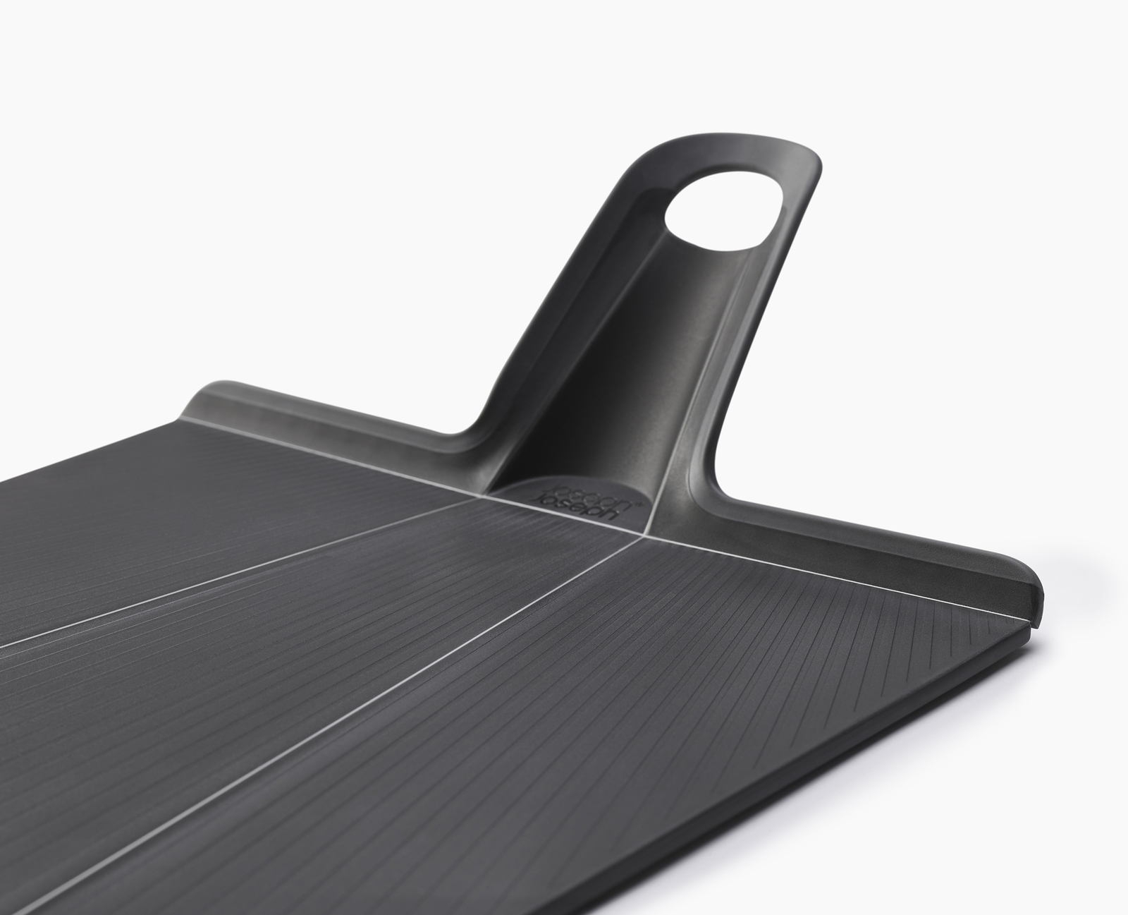 La imagen muestra un primer plano en ángulo de una tabla de cortar negra con un asa, que muestra su diseño.