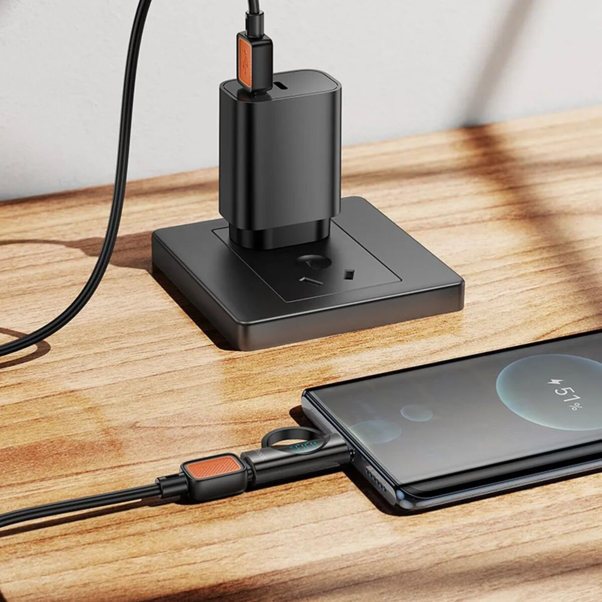 Ein schwarzes Telefon, das mit einem schwarzen Ladegerät geladen wird. Das Telefon zeigt einen Ladevorgang bei 51 % an.