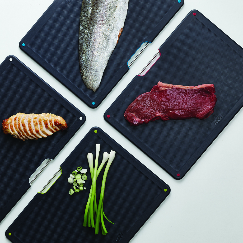 Tablas de cortar con comida: pescado, pollo en rodajas, bistec, cebolletas. Diferentes colores.