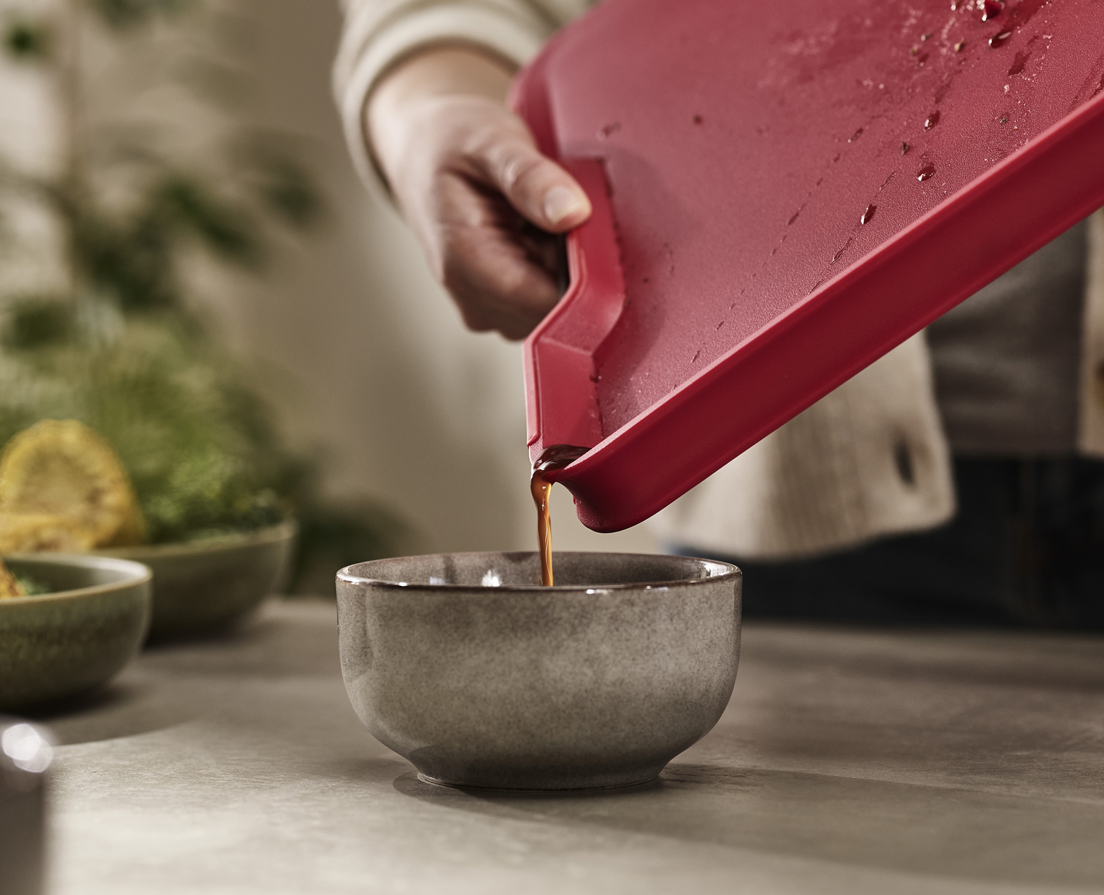 Una persona vierte líquido de una tabla roja en un cuenco gris.