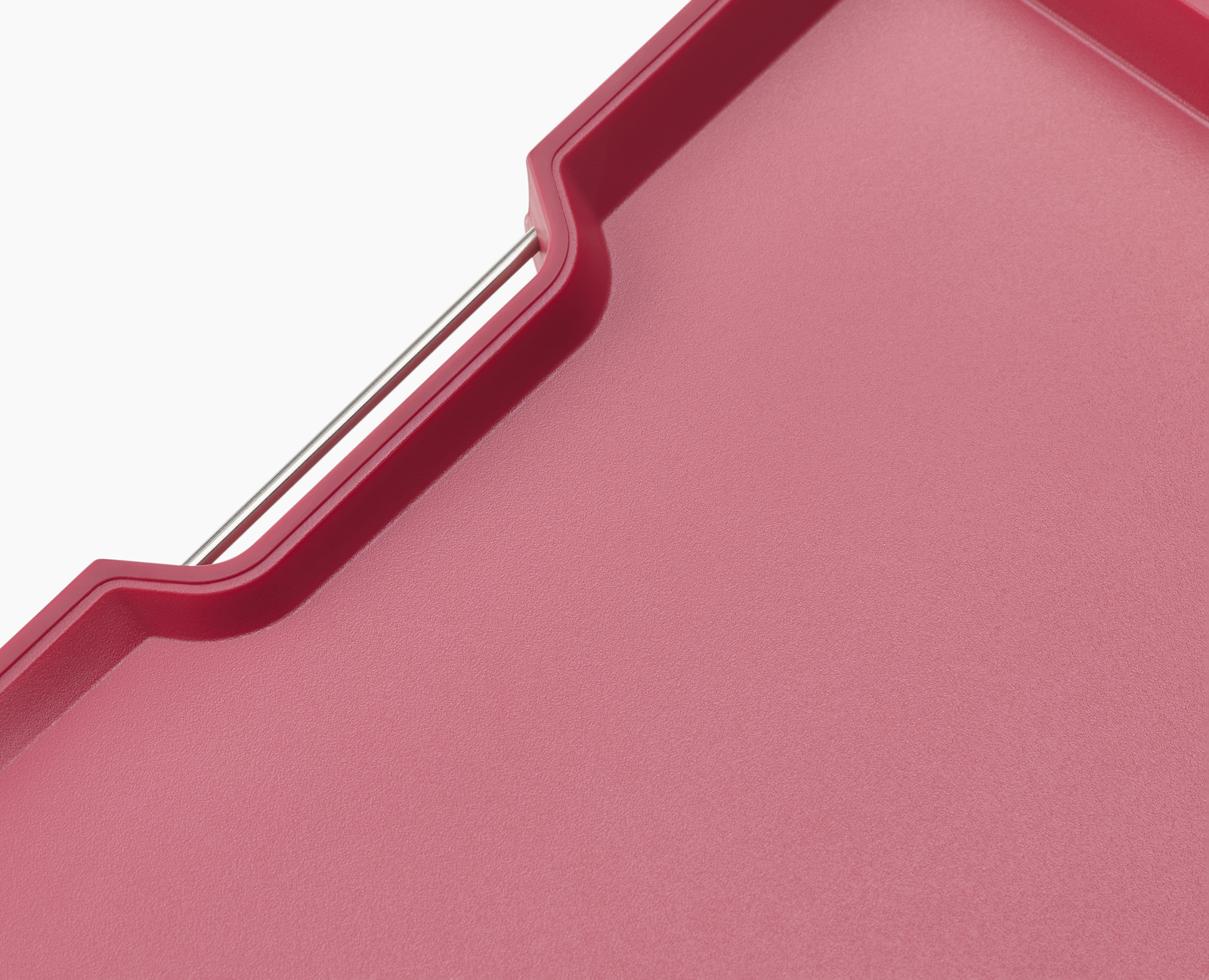 Primer plano de una tabla de cortar roja. Parte de un asa plateada es visible en el lateral.