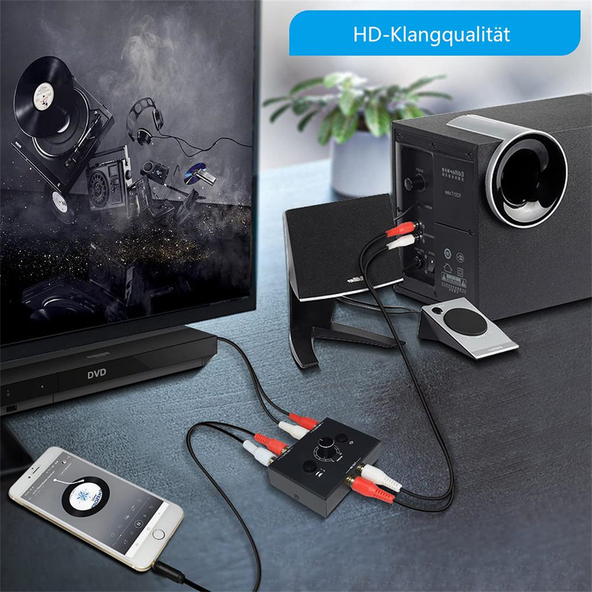 Audio-Setup mit Geräten, die an einen schwarzen Audio-Mixer angeschlossen sind. Telefon und Lautsprecher sichtbar.