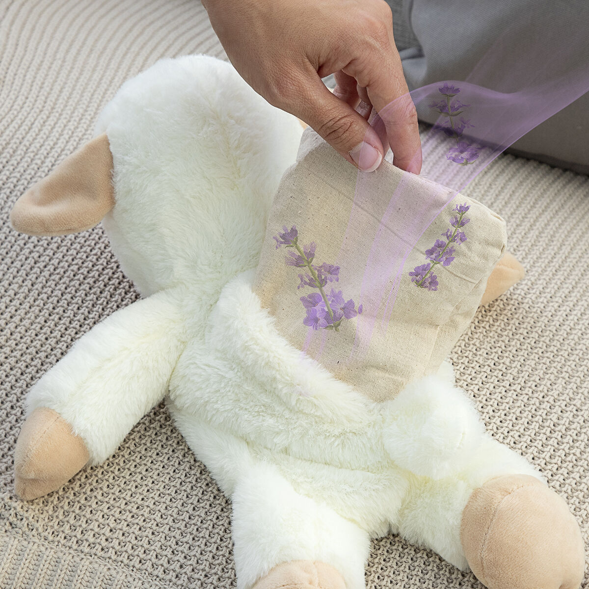 Una mano posiziona un sacchetto di lavanda su un peluche di agnello.