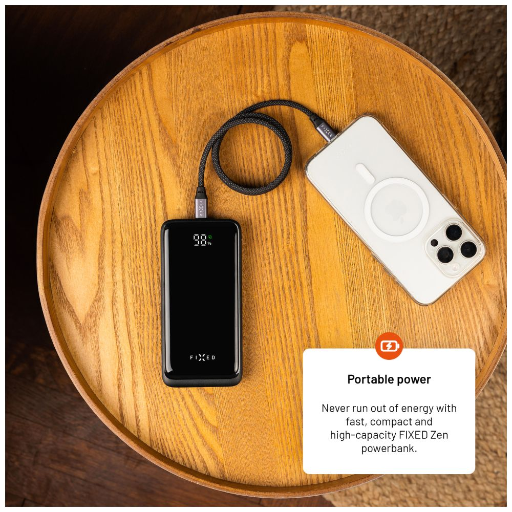 Eine schwarze Powerbank, die mit einem weißen Telefon auf einem Holztisch verbunden ist. Text: Portable Power.