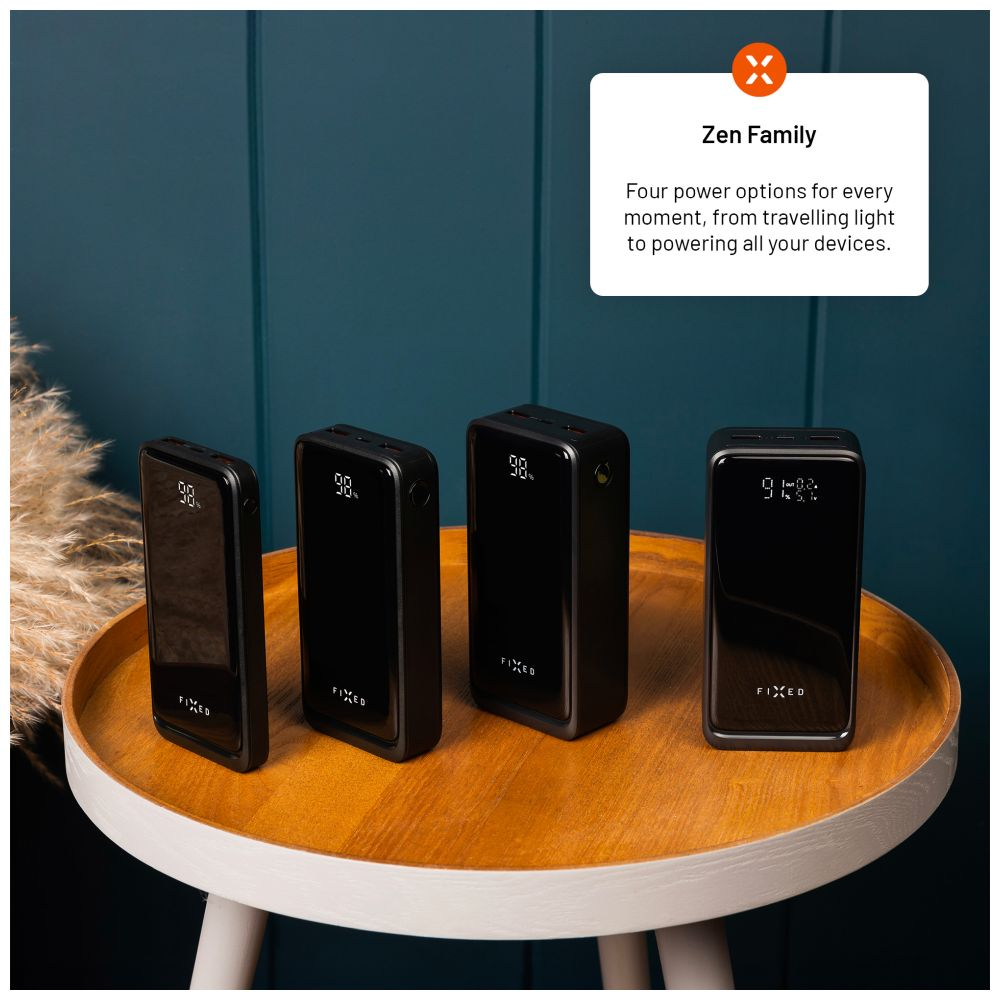 Vier schwarze Powerbanks auf einem Holztisch. Jede hat ein Display, das den Akkuladestand anzeigt.