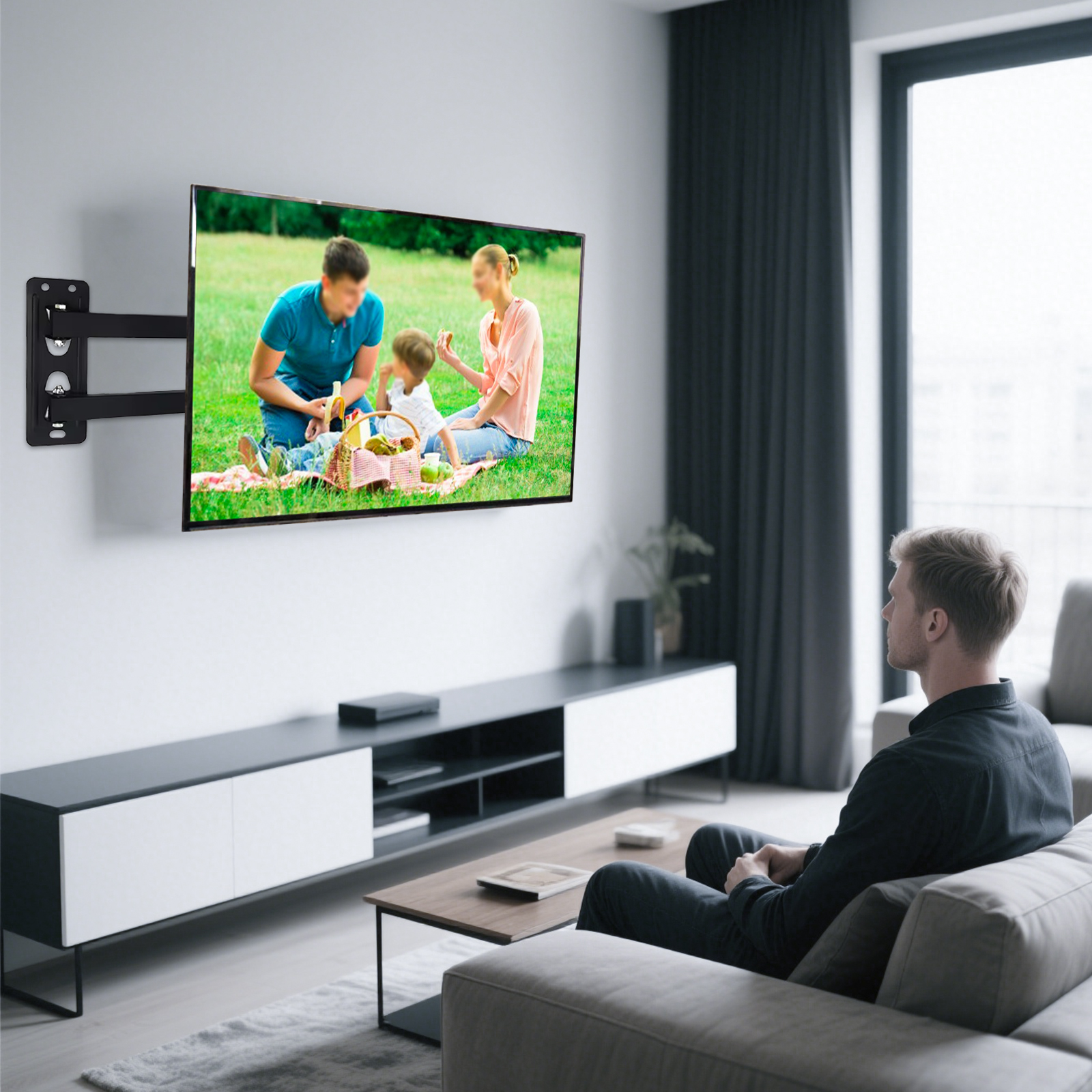 Mann sitzt auf Sofa, sieht TV an Wand mit Familienpicknick.