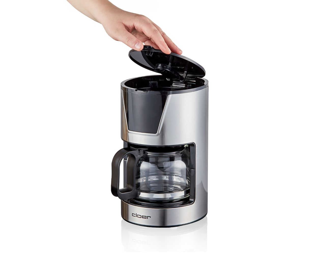 Ręka otwierająca pokrywę srebrno-czarnego ekspresu do kawy, na białym tle.