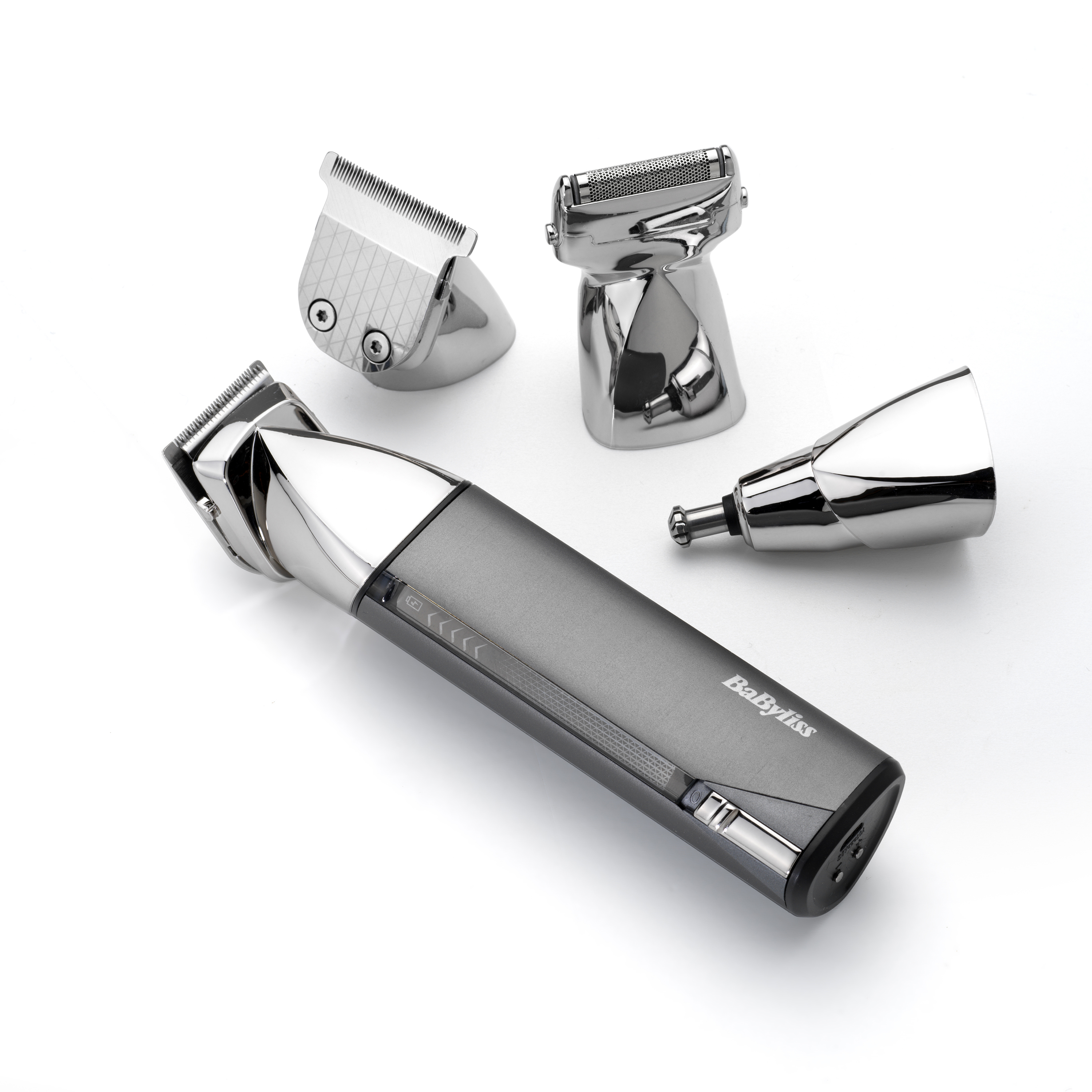 Una cortadora de cabello Babyliss plateada y gris con tres accesorios sobre una superficie blanca.