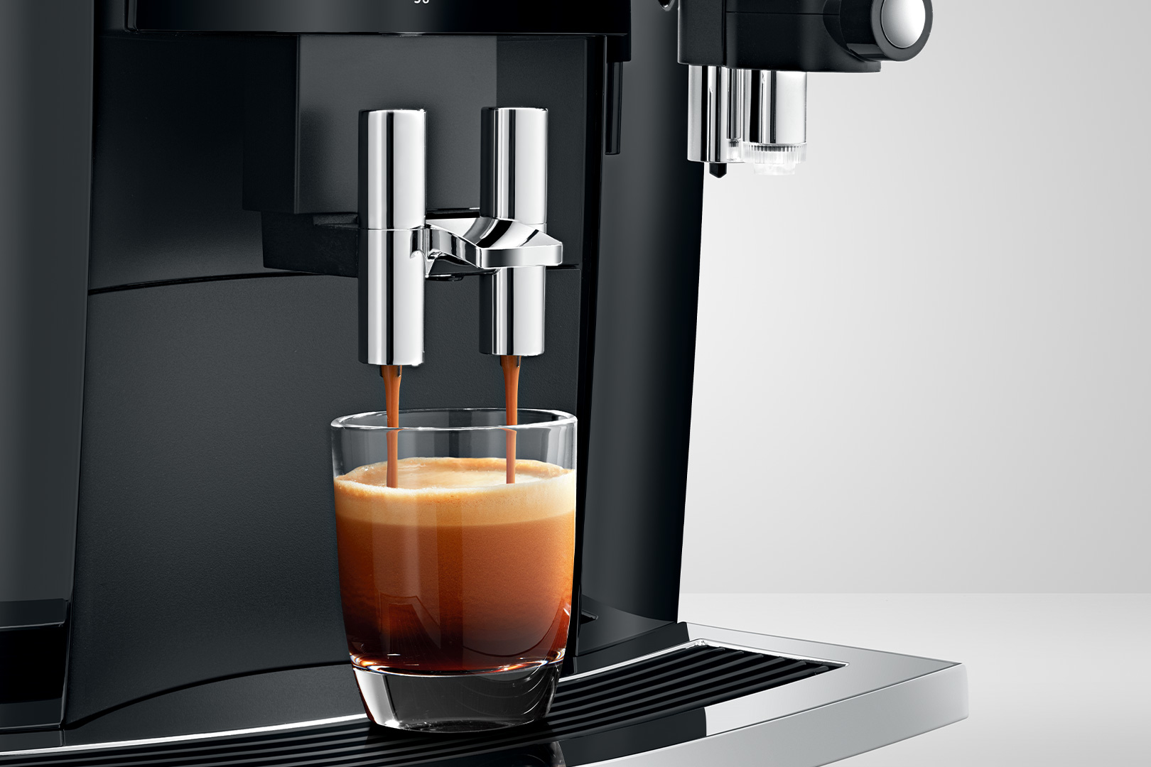 Espressomaschine, die ein Glas mit Espresso füllt. Die Maschine ist schwarz und silber.