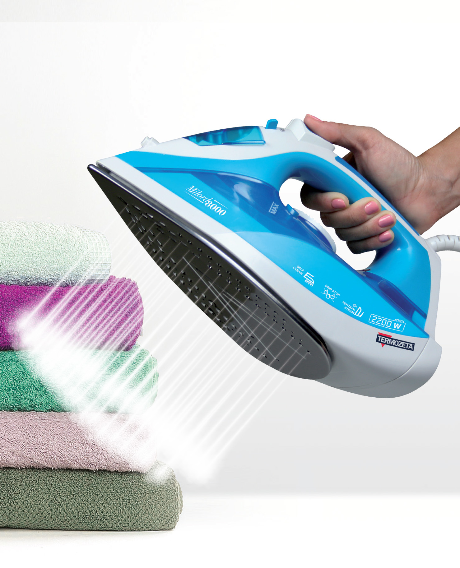 Niebieskie żelazko trzymane nad stosem ręczników, wydobywa się para.