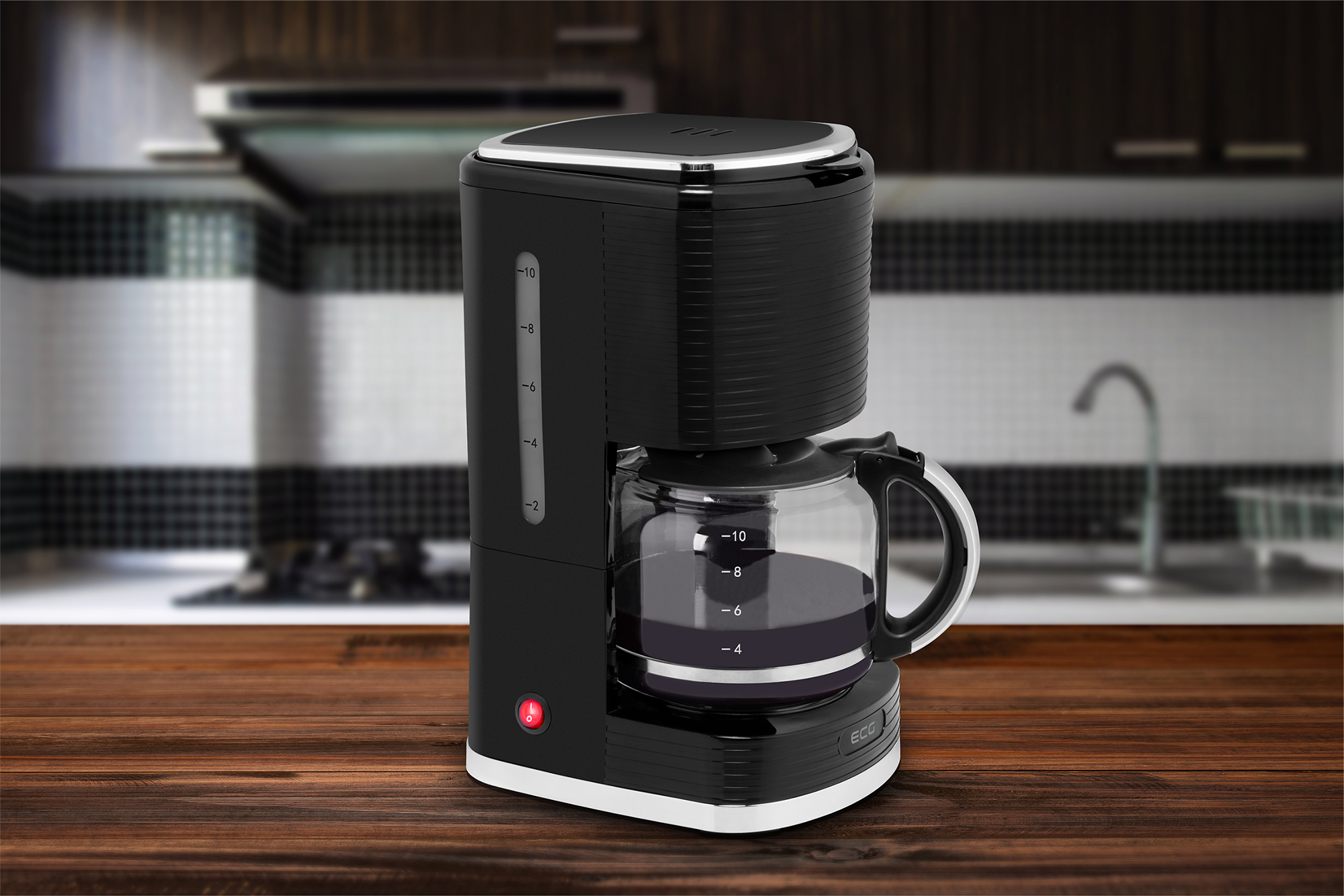 Czarny ekspres do kawy na drewnianym stole. W tle kuchnia z białymi kafelkami.