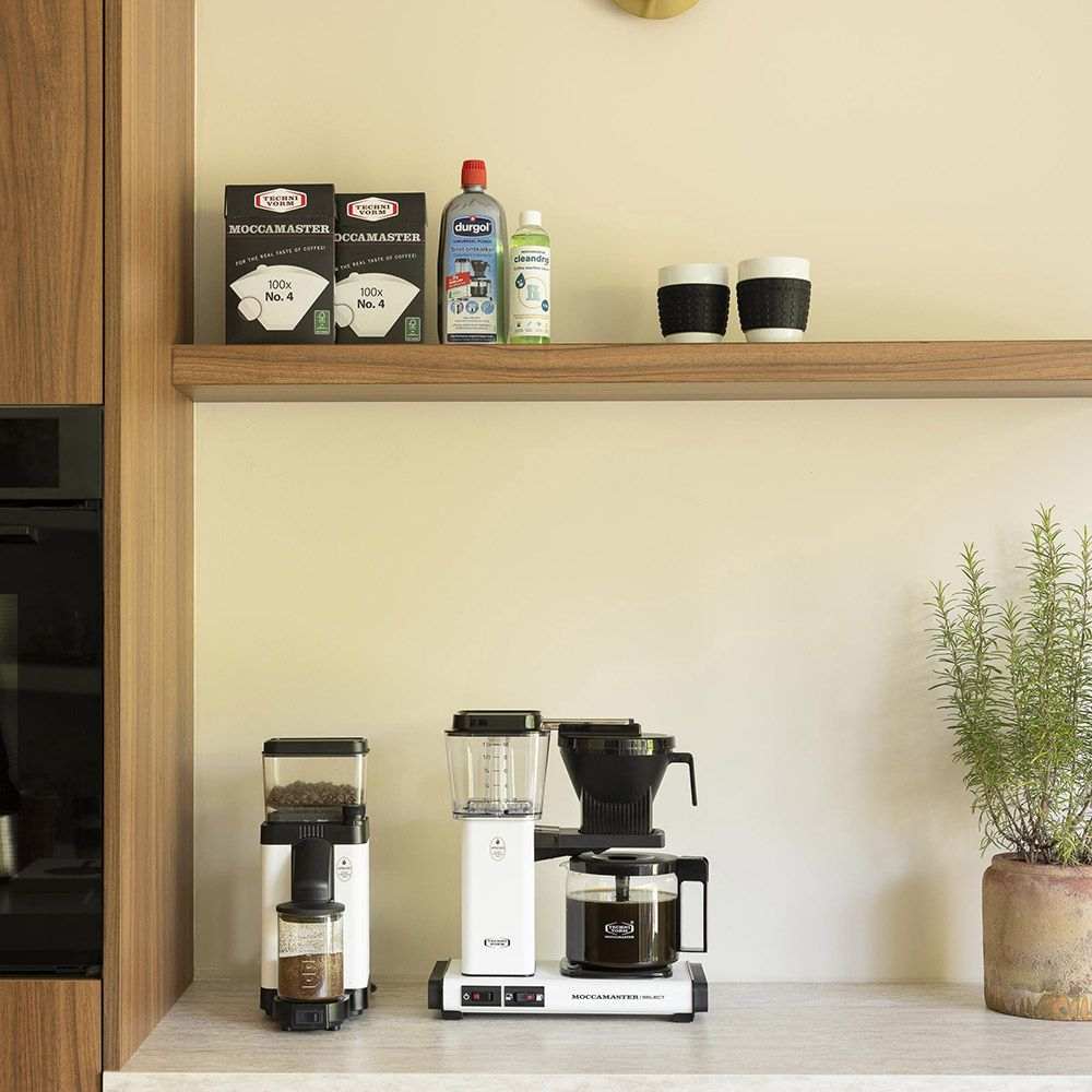 Ekspres do kawy i akcesoria na blacie. Dwie filiżanki, środki czyszczące, kawa.