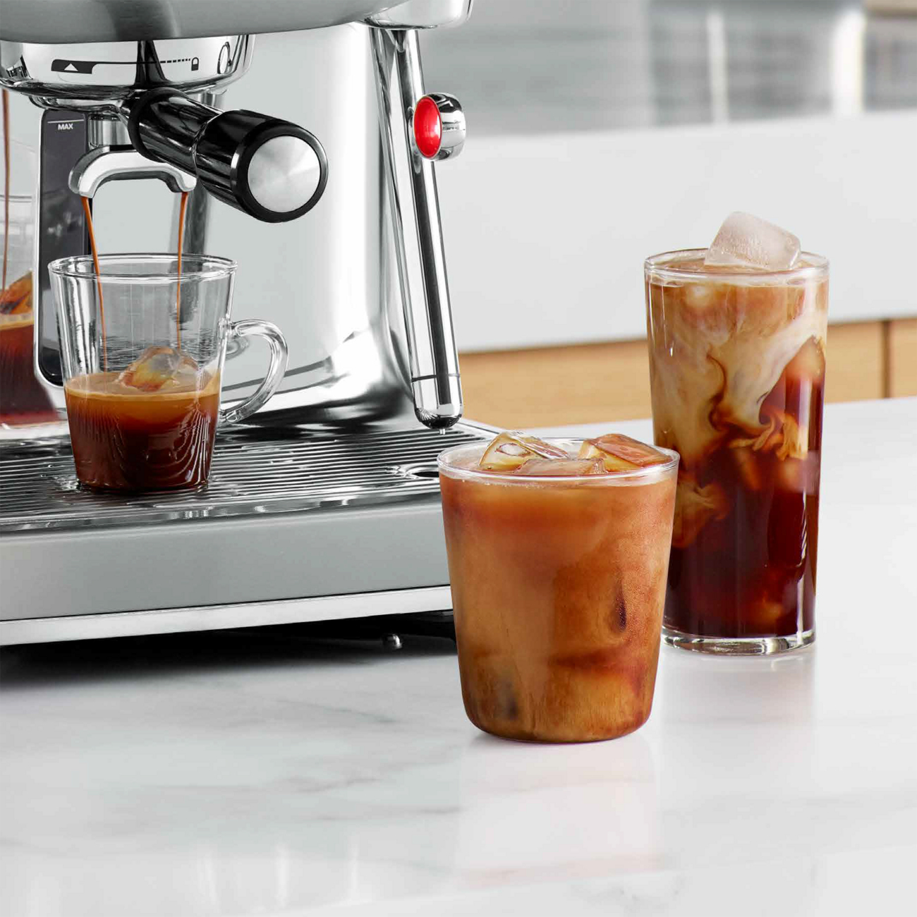 Una macchina per espresso argentata con scatti di espresso e bevande al caffè freddo.