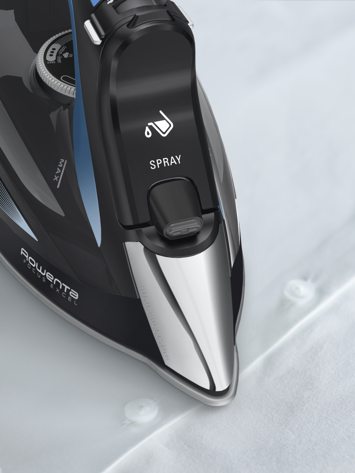 Zbliżenie czarnego żelazka z niebieskimi akcentami na białej tkaninie.