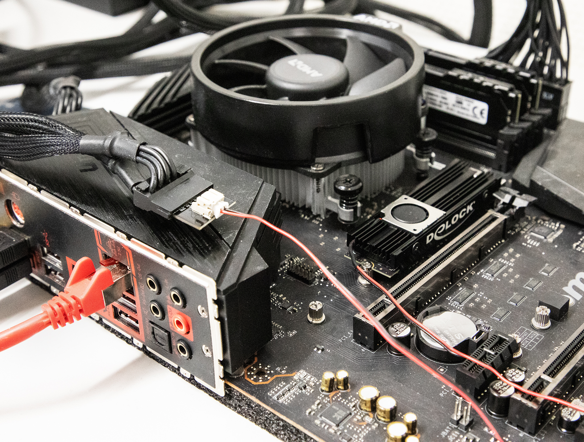 Scheda madre con ventola CPU, cavi rossi e un dissipatore nero.