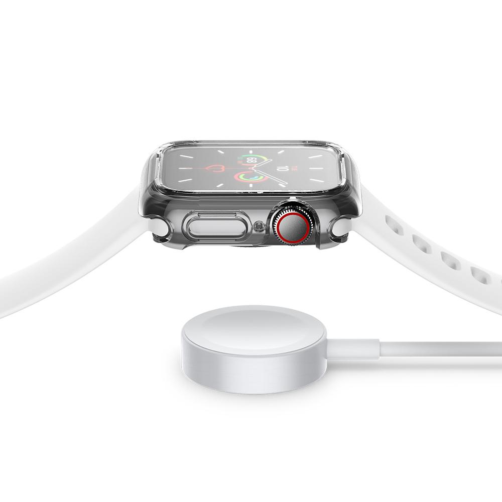 An Apple Watch with a white strap charging on a white charging pad. The watch has a clear case.