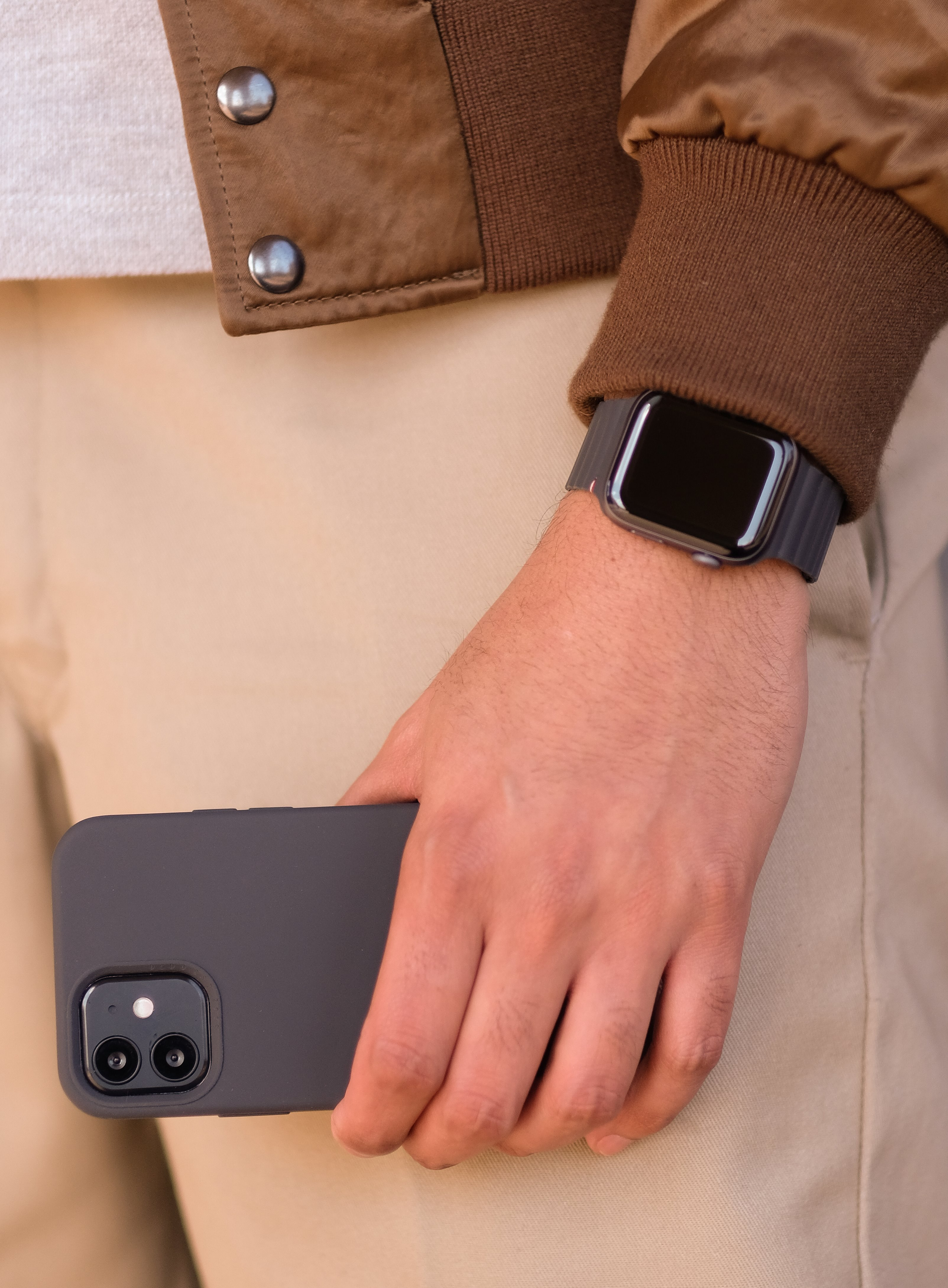 Osoba trzymająca telefon, nosząca Apple Watch na nadgarstku. Swobodny strój.