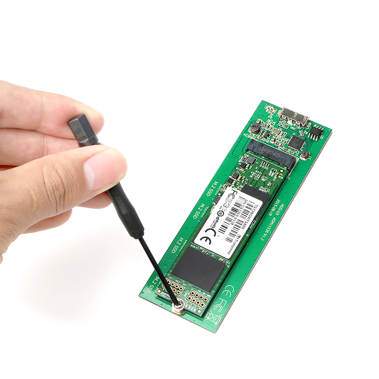 Hand, die mit einem Schraubendreher eine M.2 SSD auf einer grünen Leiterplatte installiert.