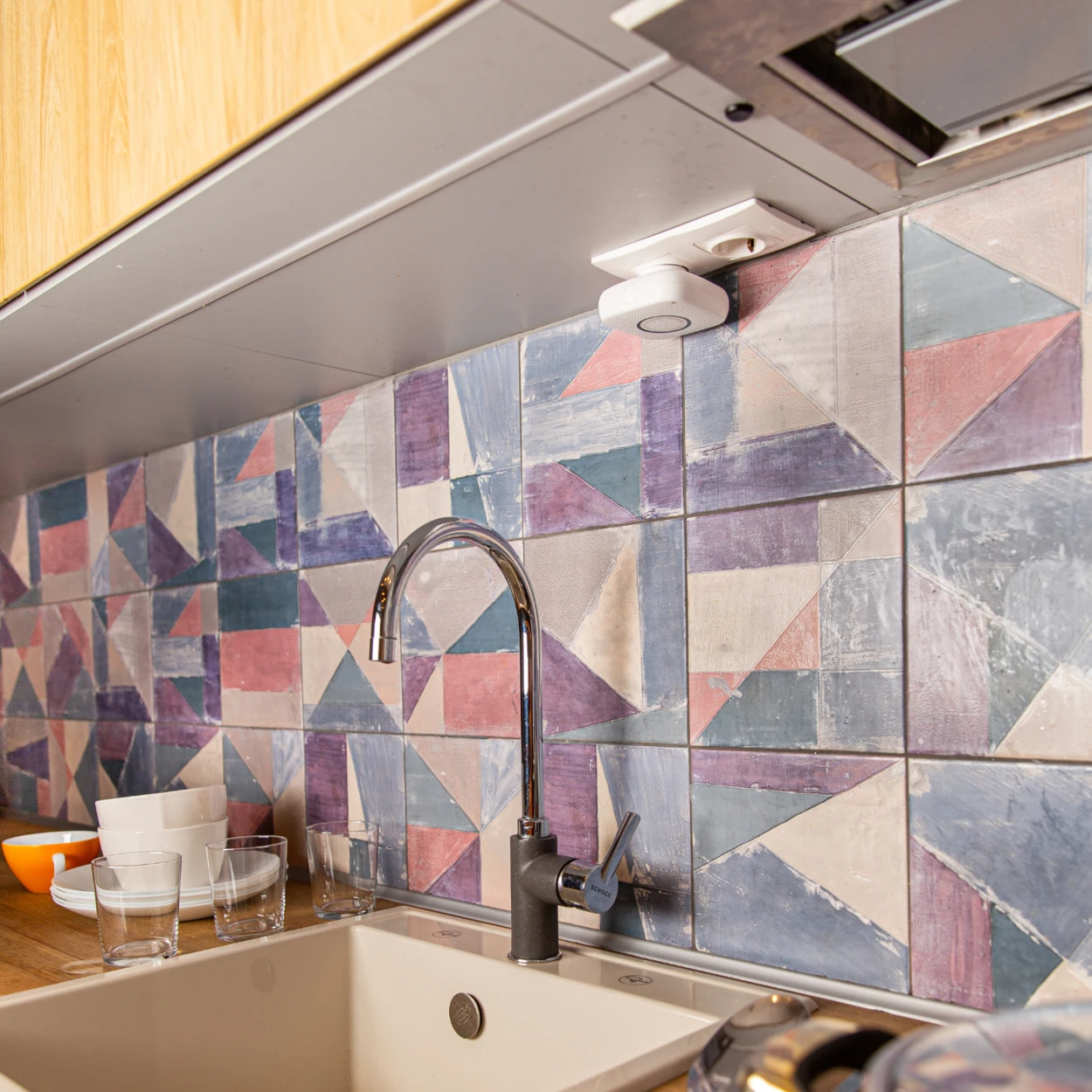 Zlewozmywak z kranem, kolorowe płytki i inteligentne urządzenie.