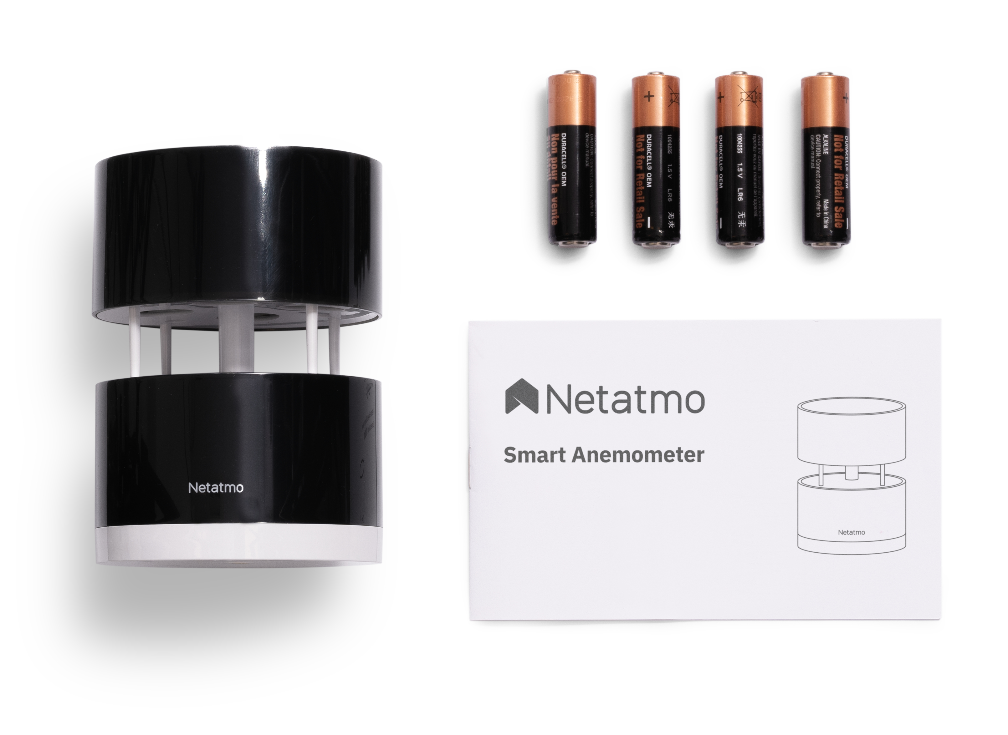 A smart anemometer, batteries, and a manual on a white surface.