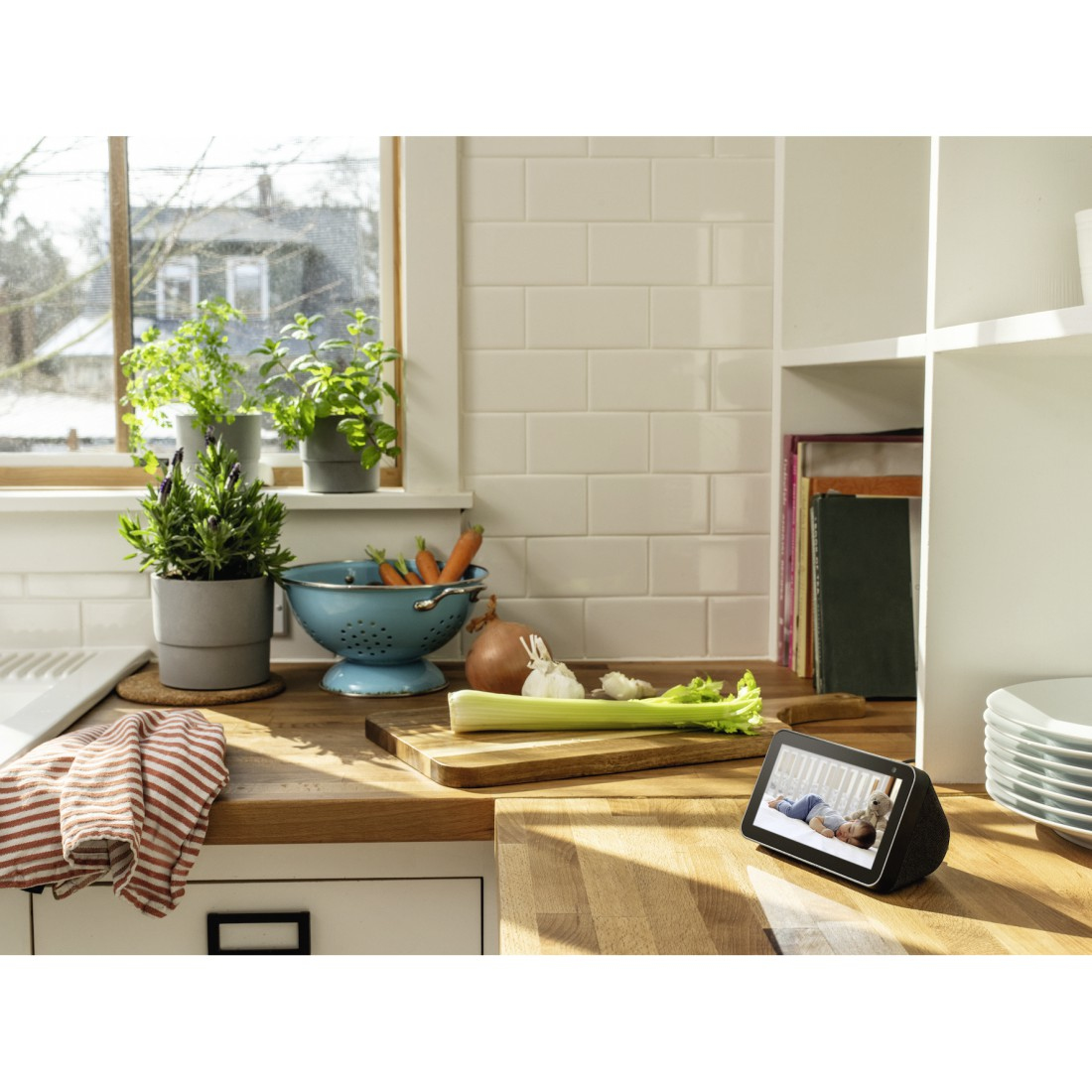 Scena kuchenna z inteligentnym wyświetlaczem pokazującym dziecko, warzywa i okno.