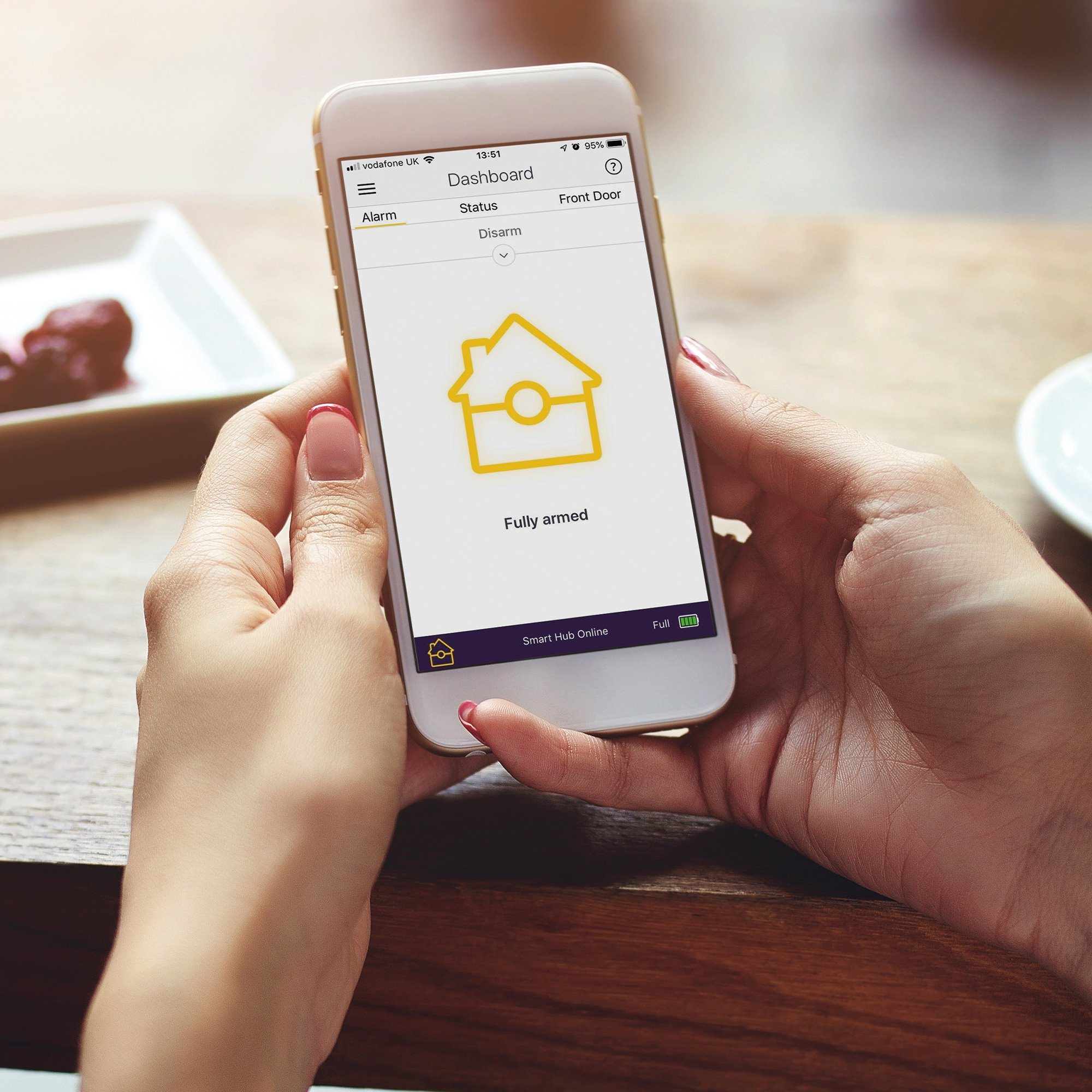 Eine Person hält ein Telefon, das ein Smart-Home-Dashboard anzeigt. Die Anzeige zeigt ein Haus-Symbol.