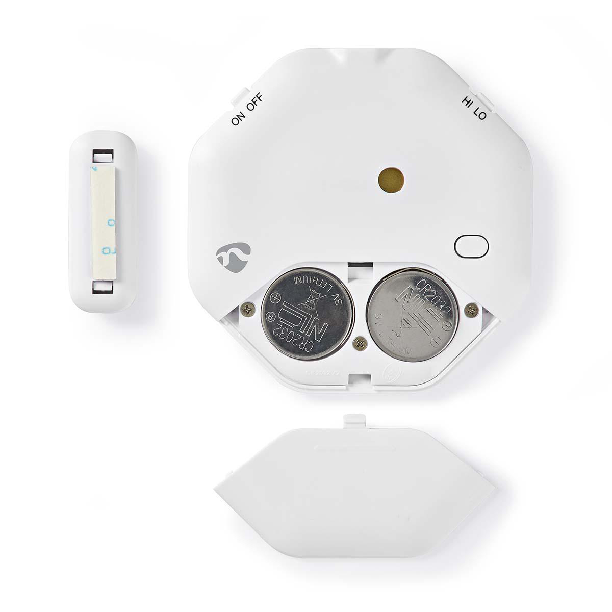 Dispositivo bianco con vano batteria aperto, che mostra due batterie CR2032. Un piccolo rettangolo bianco a sinistra.