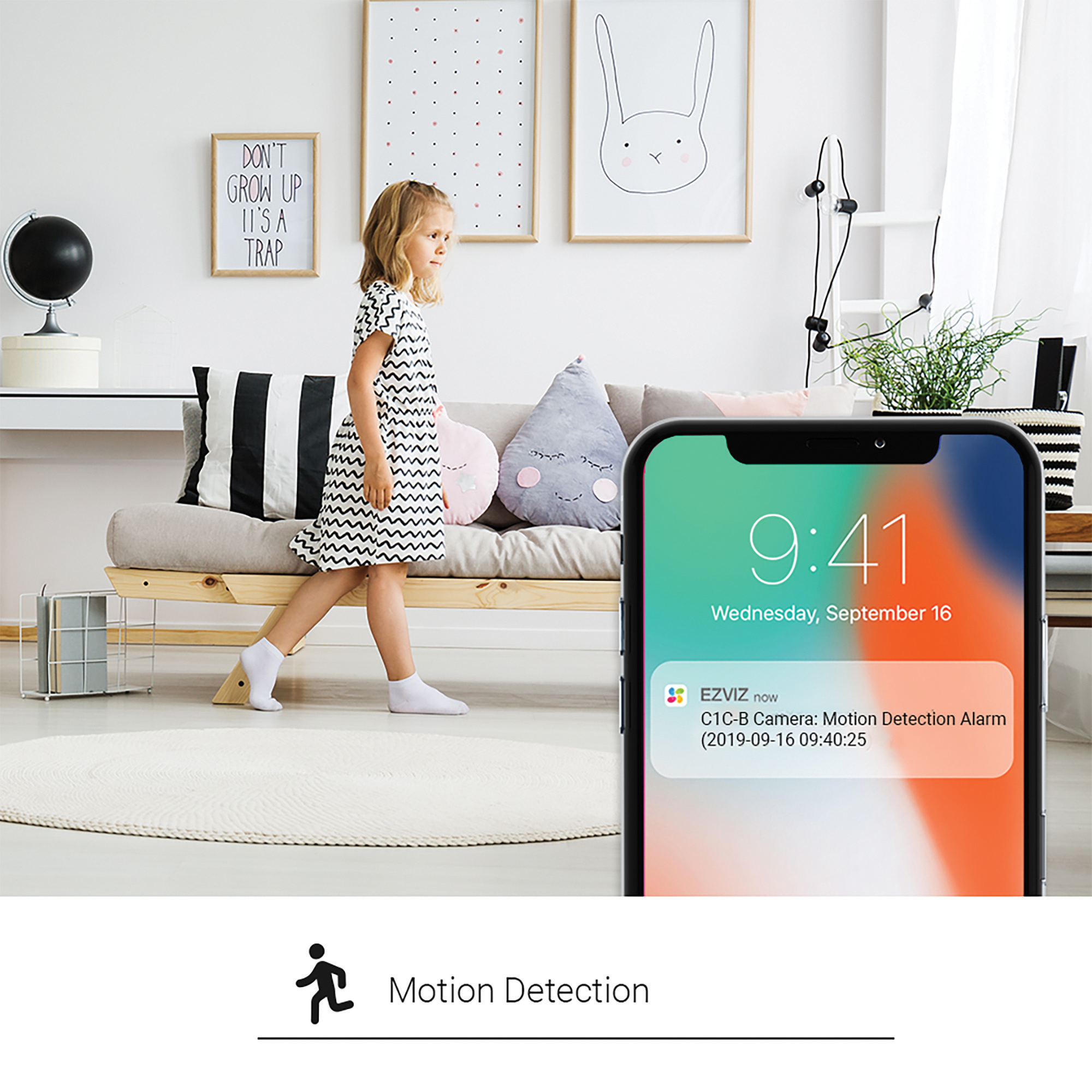 Dziewczyna idąca w pokoju z telefonem pokazującym alert wykrywania ruchu na ekranie.