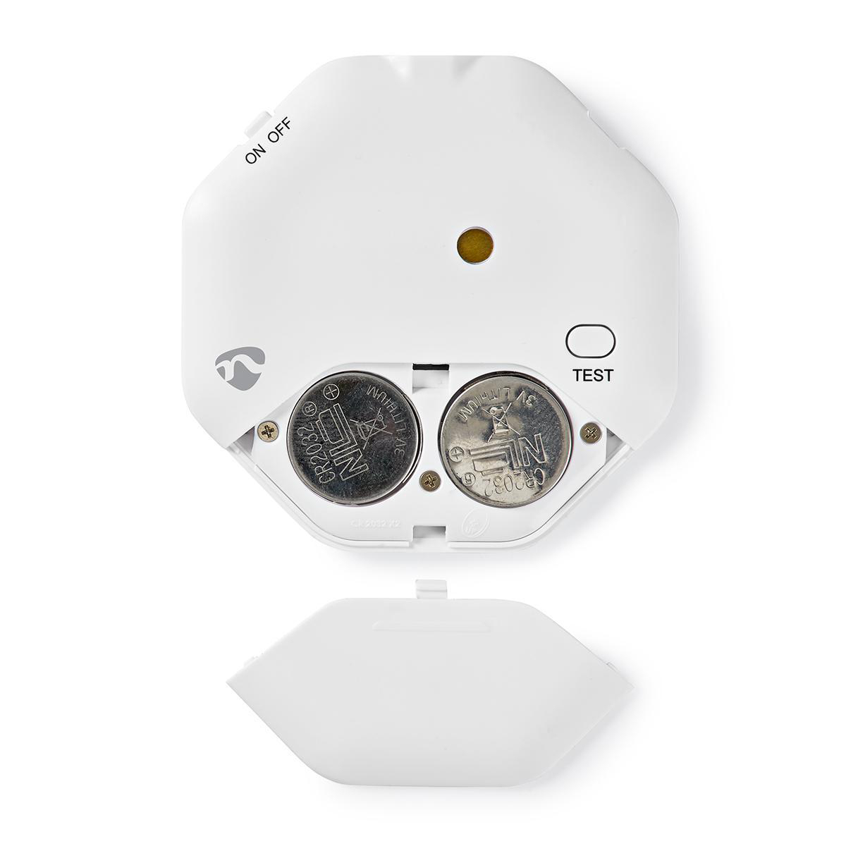 Otwarty czujnik dymu z dwiema bateriami i przyciskiem testu.