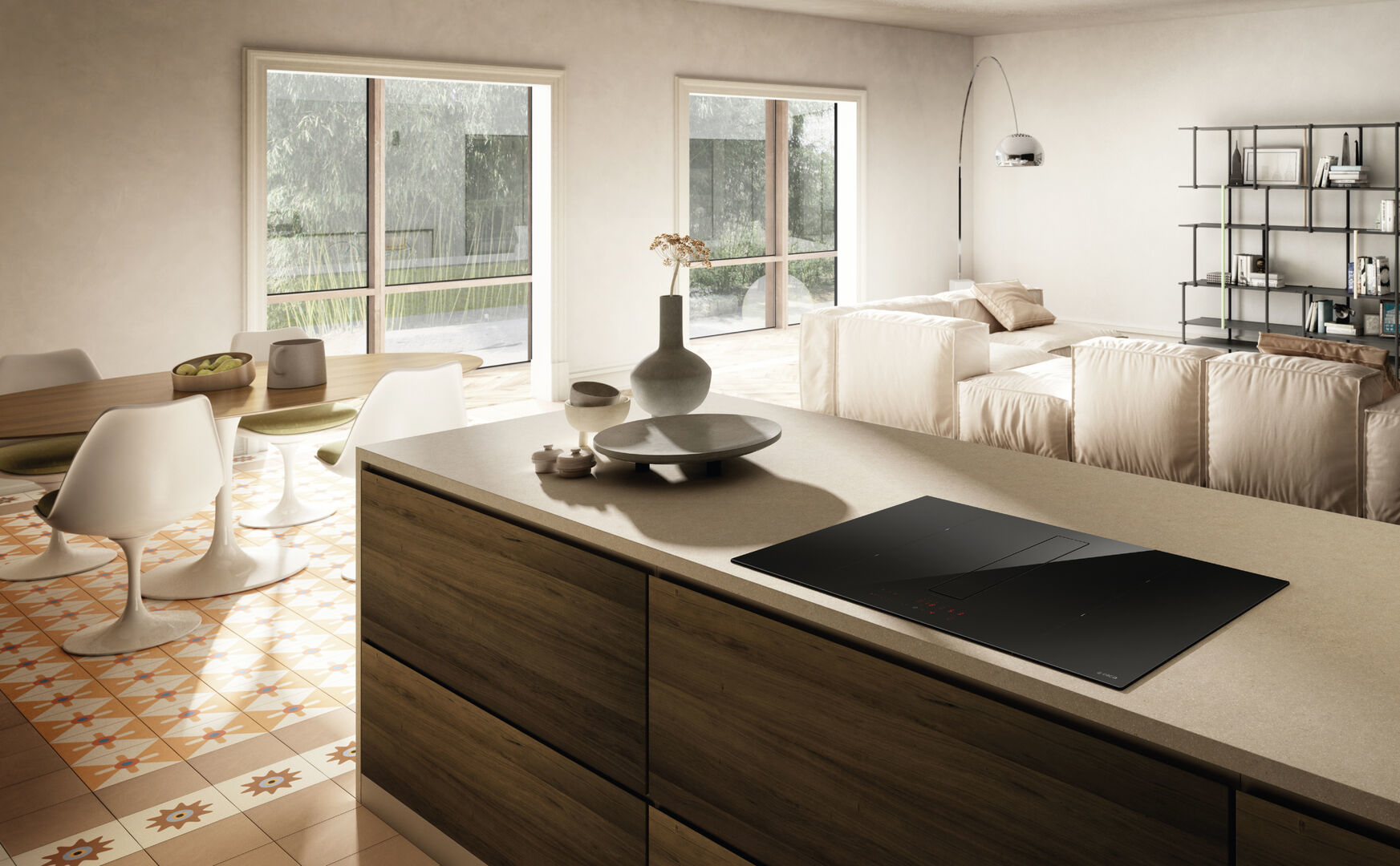 Wnętrze kuchni z wyspą kuchenną. Czarna płyta grzewcza na wyspie. Stół z krzesłami. Salon w tle.