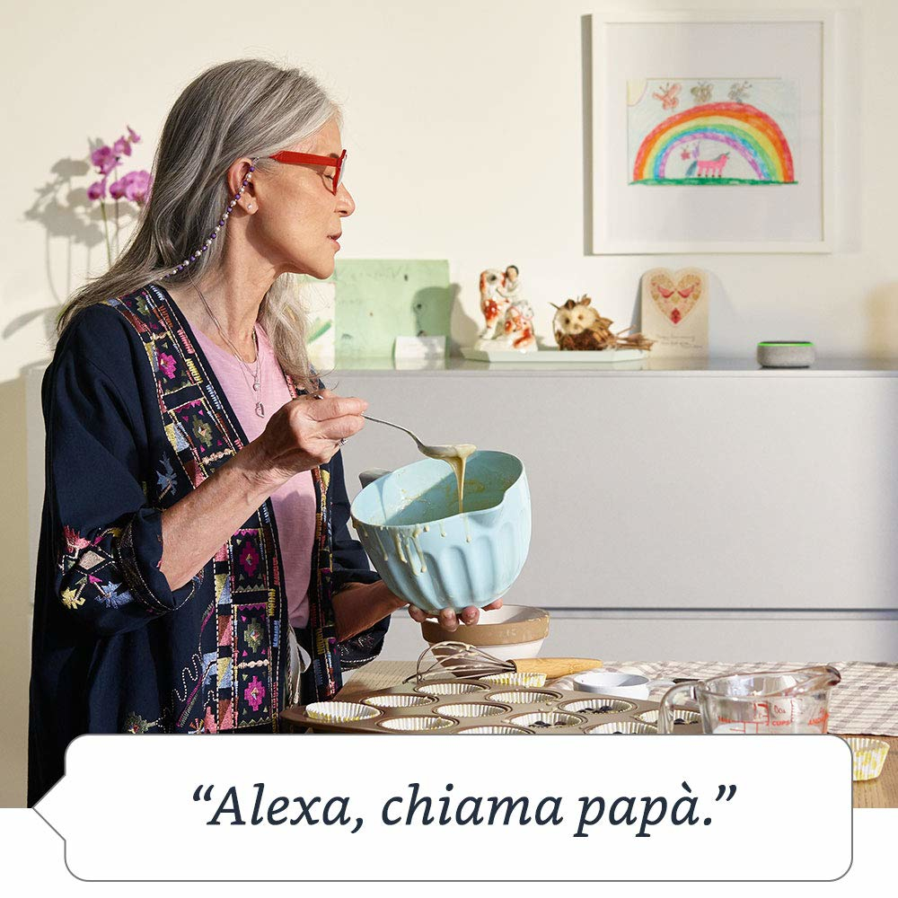 Eine Frau gießt Teig in Muffinformen. Eine Regenbogenzeichnung ist an der Wand. Der Text lautet: „Alexa, ruf Papa an“.