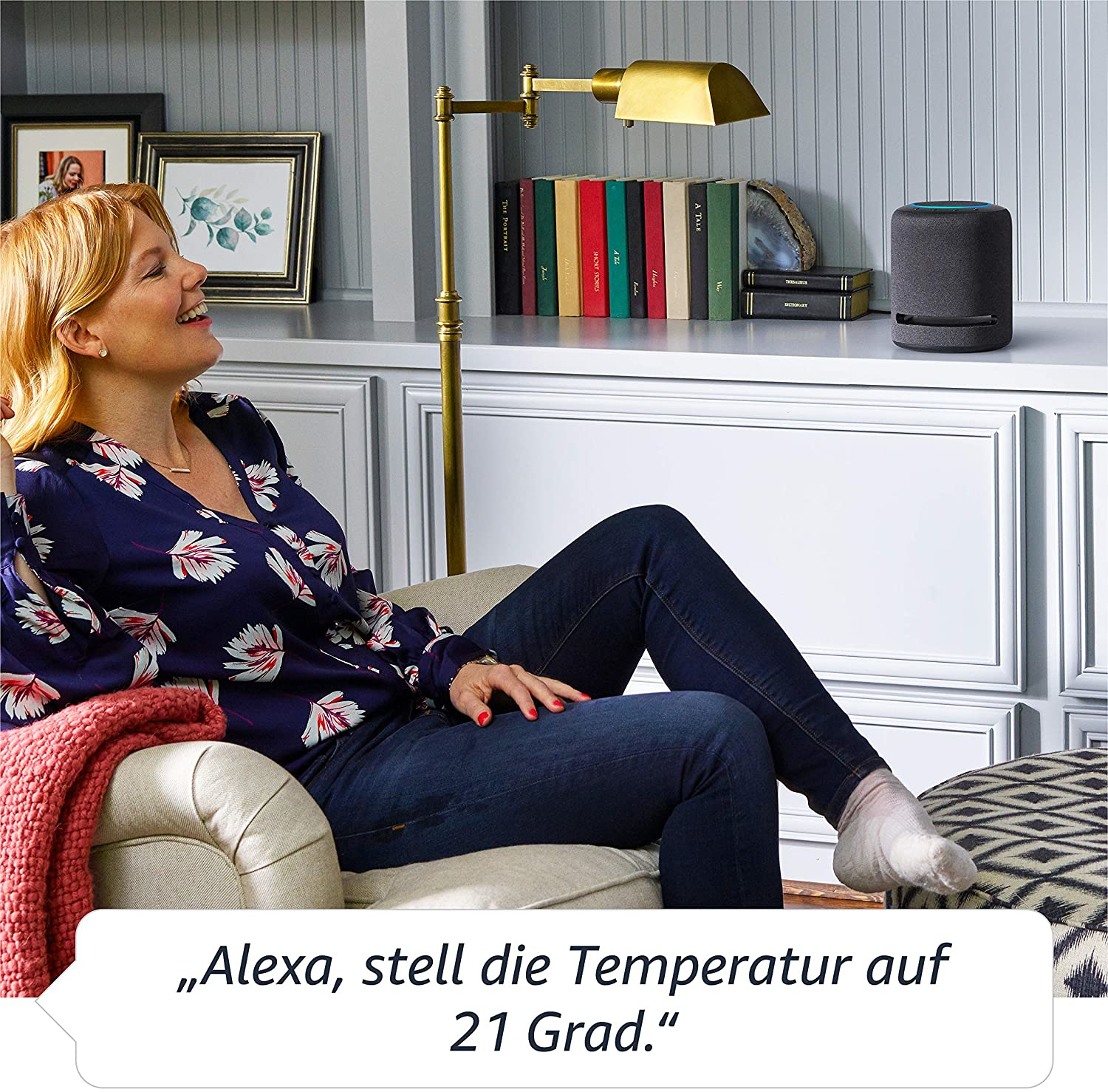 Frau im Wohnzimmer mit Smart Speaker, sagt: 'Alexa, stelle die Temperatur auf 21 Grad'.