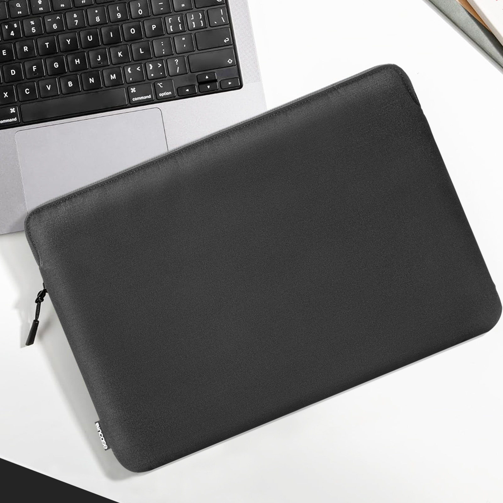 Custodia nera per laptop su una scrivania bianca con un laptop sopra.