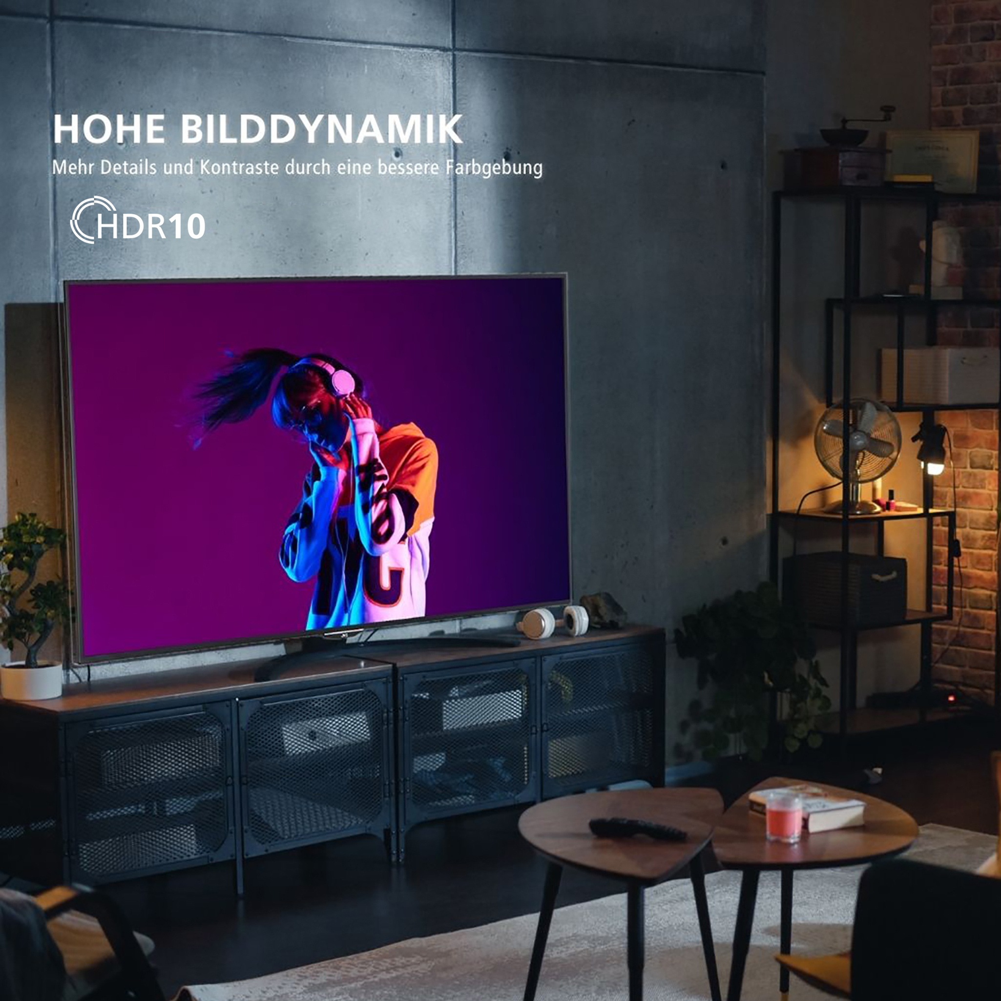 TV pokazujący kobietę słuchającą muzyki. Nowoczesny pokój, ciemne meble, słuchawki na stole.